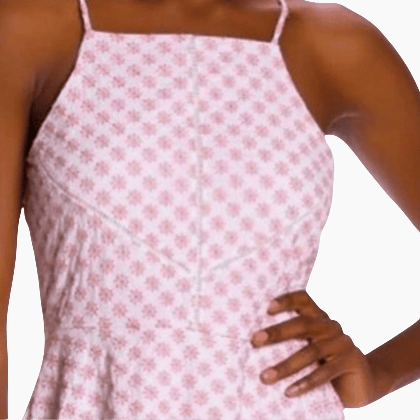 Woman wearing a pink floral dress with thin straps on a plain background