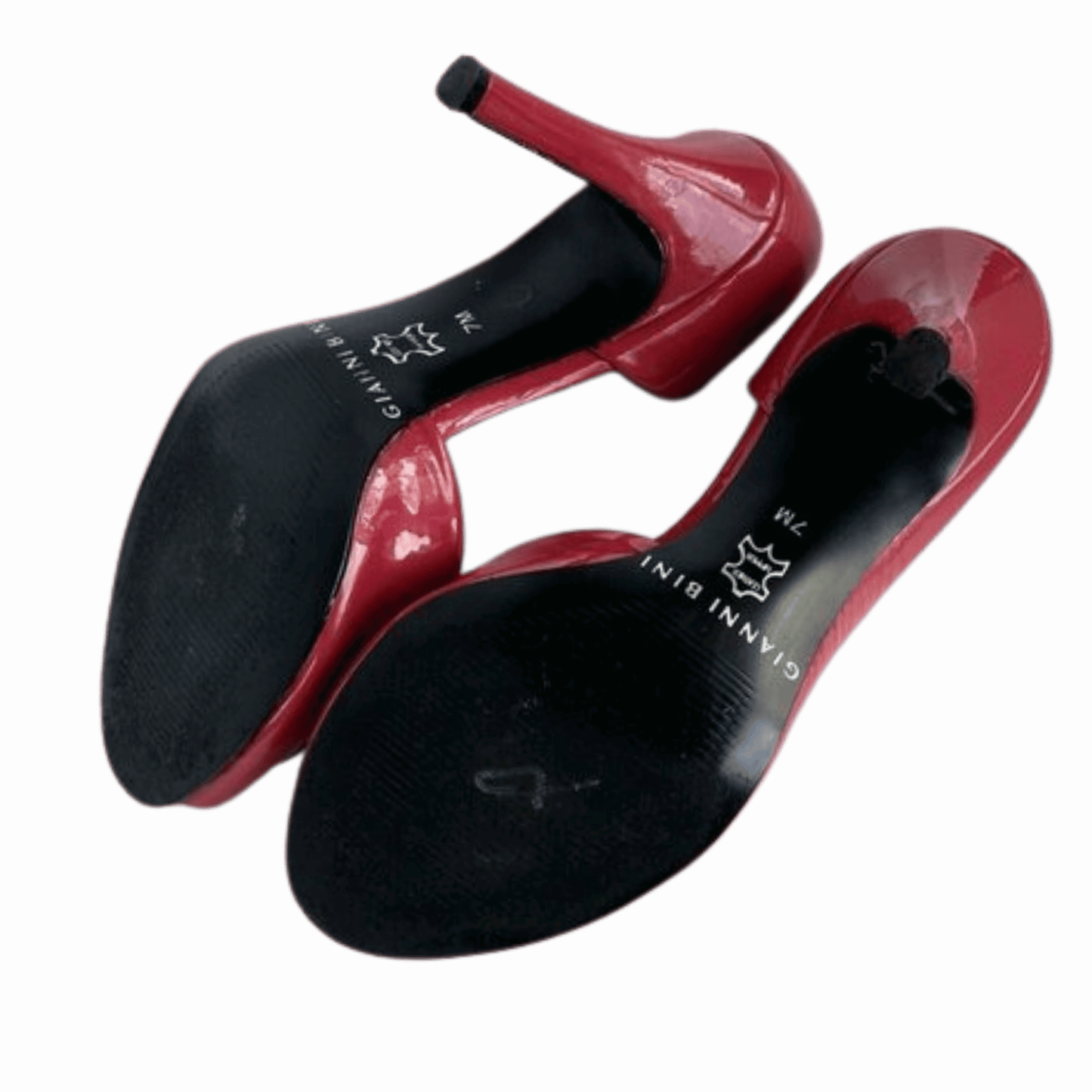 Red high-heeled shoes with black soles on a green background