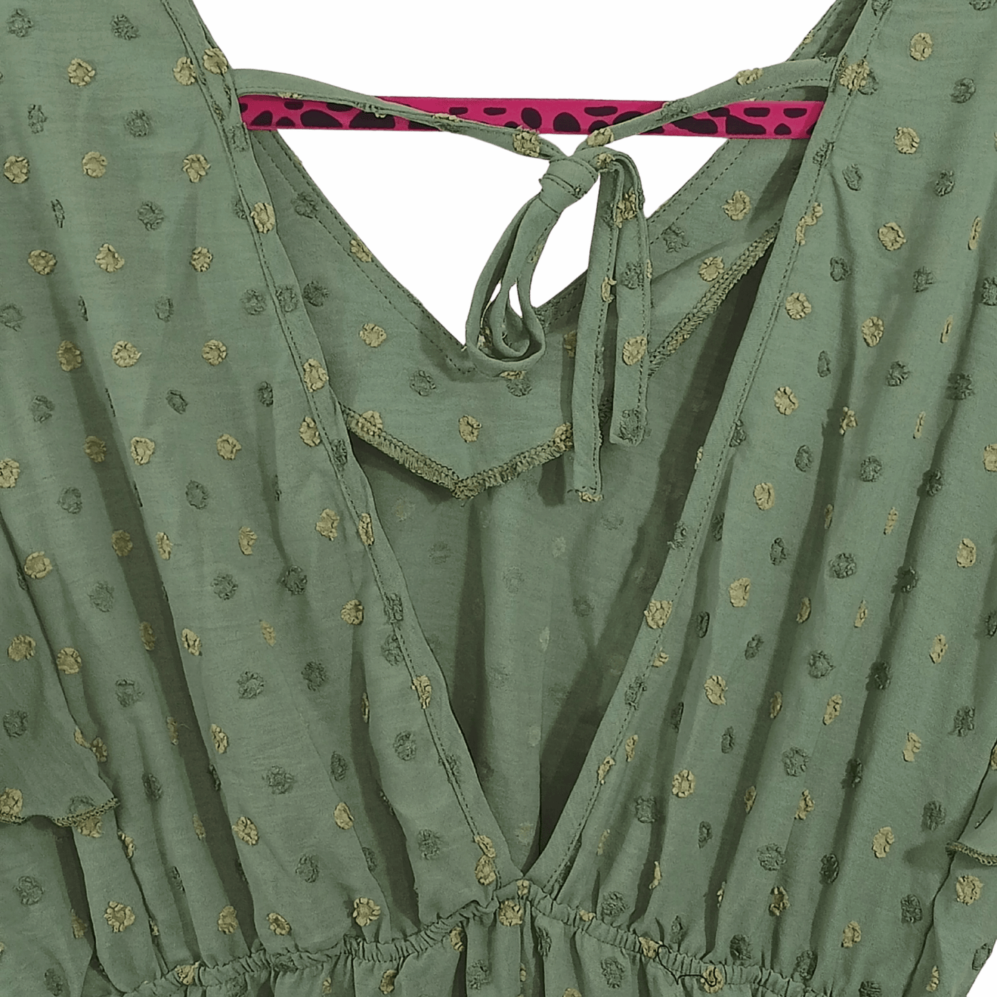 Green dress with gold floral patterns on a hanger against a gray background