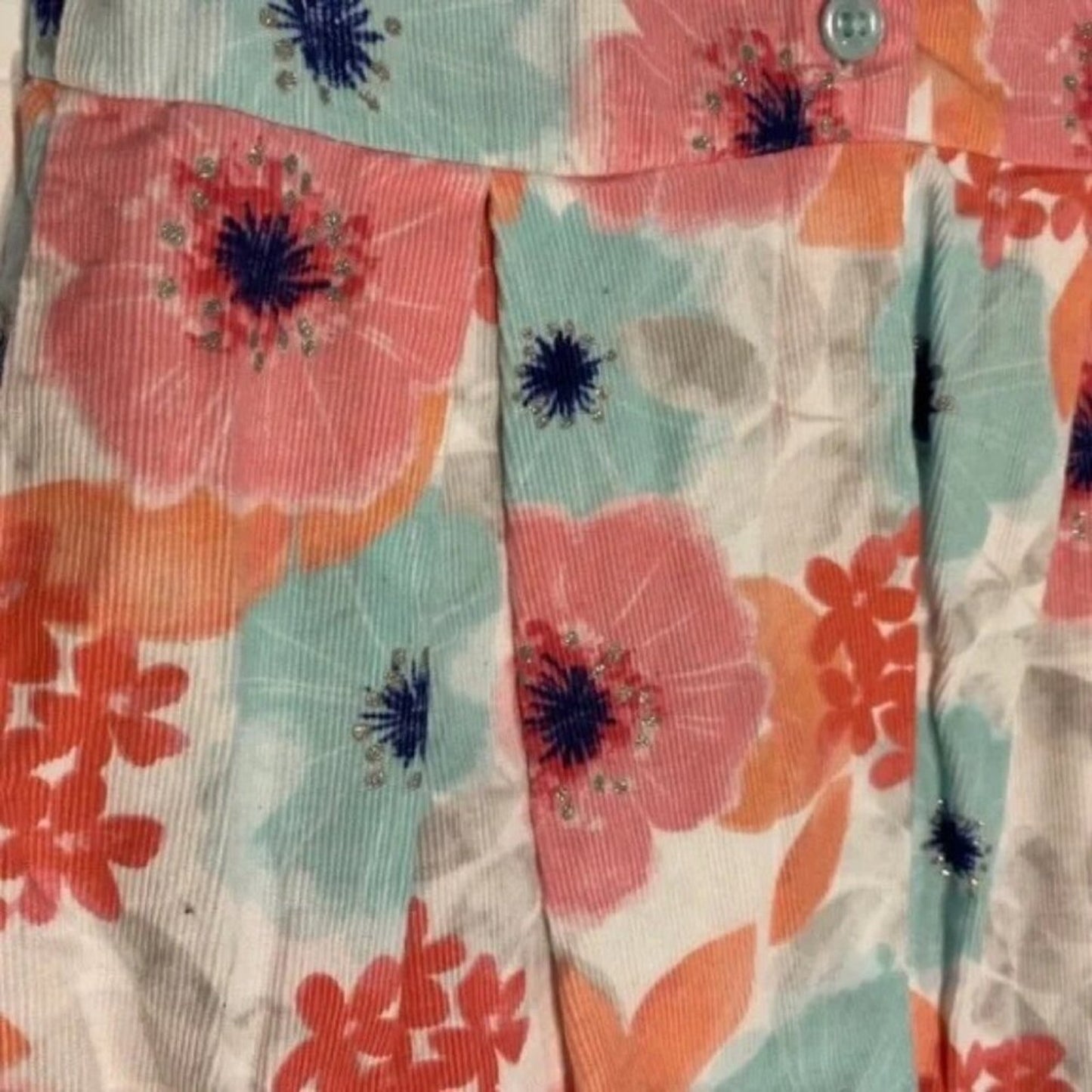 Close-up of floral fabric with pink, blue, and orange flowers on a patterned background.