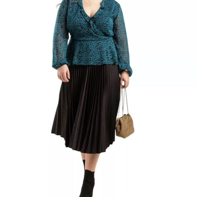 Woman wearing a teal top and black skirt with a beige handbag on a white background