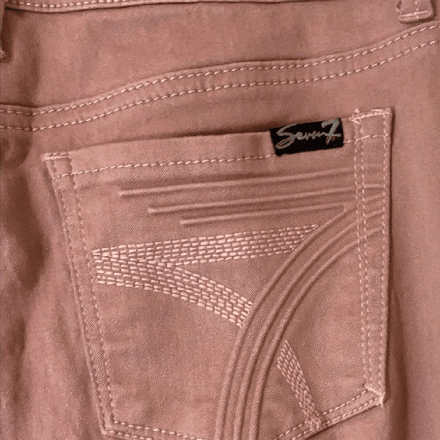 Close-up of a brown leather jacket with a brand label on the back pocket.
