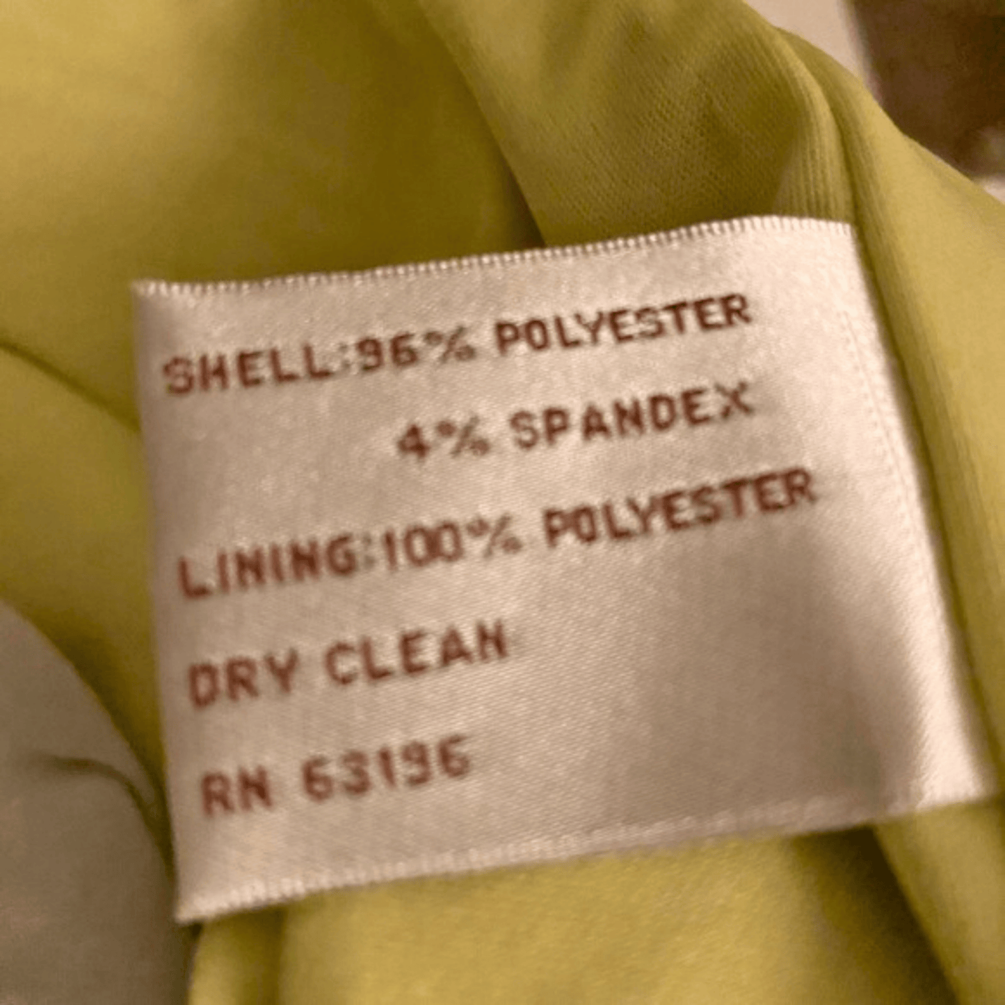 Fabrication label on a green garment with material composition details.