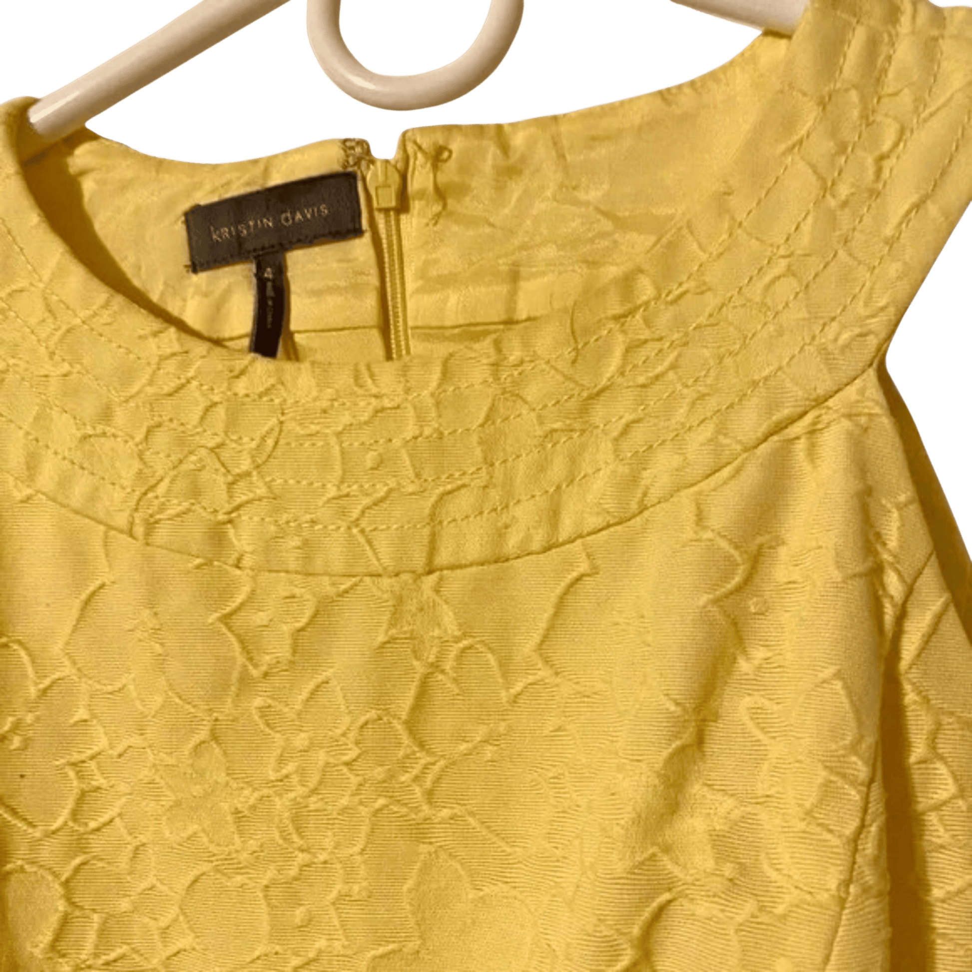 Yellow lace top on a hanger with a brand tag visible