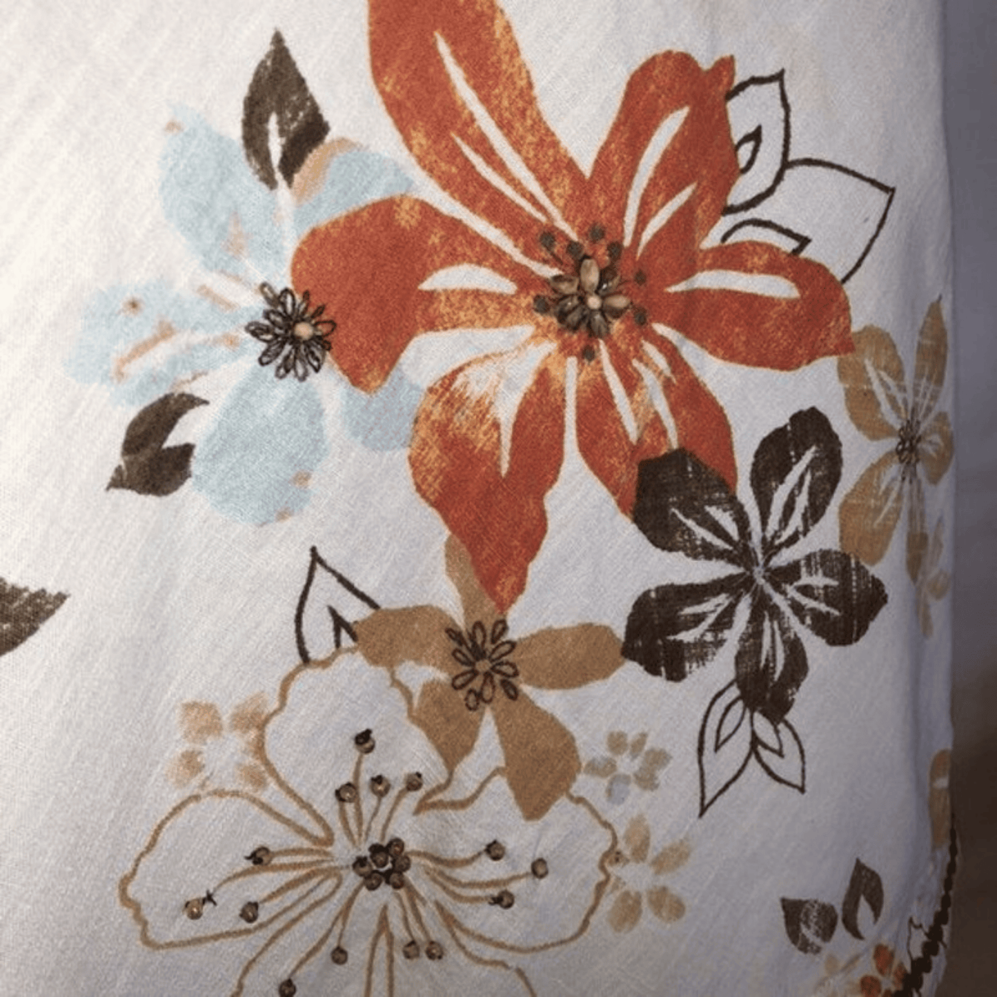 Floral patterned fabric with orange, blue, and brown flowers on a white background