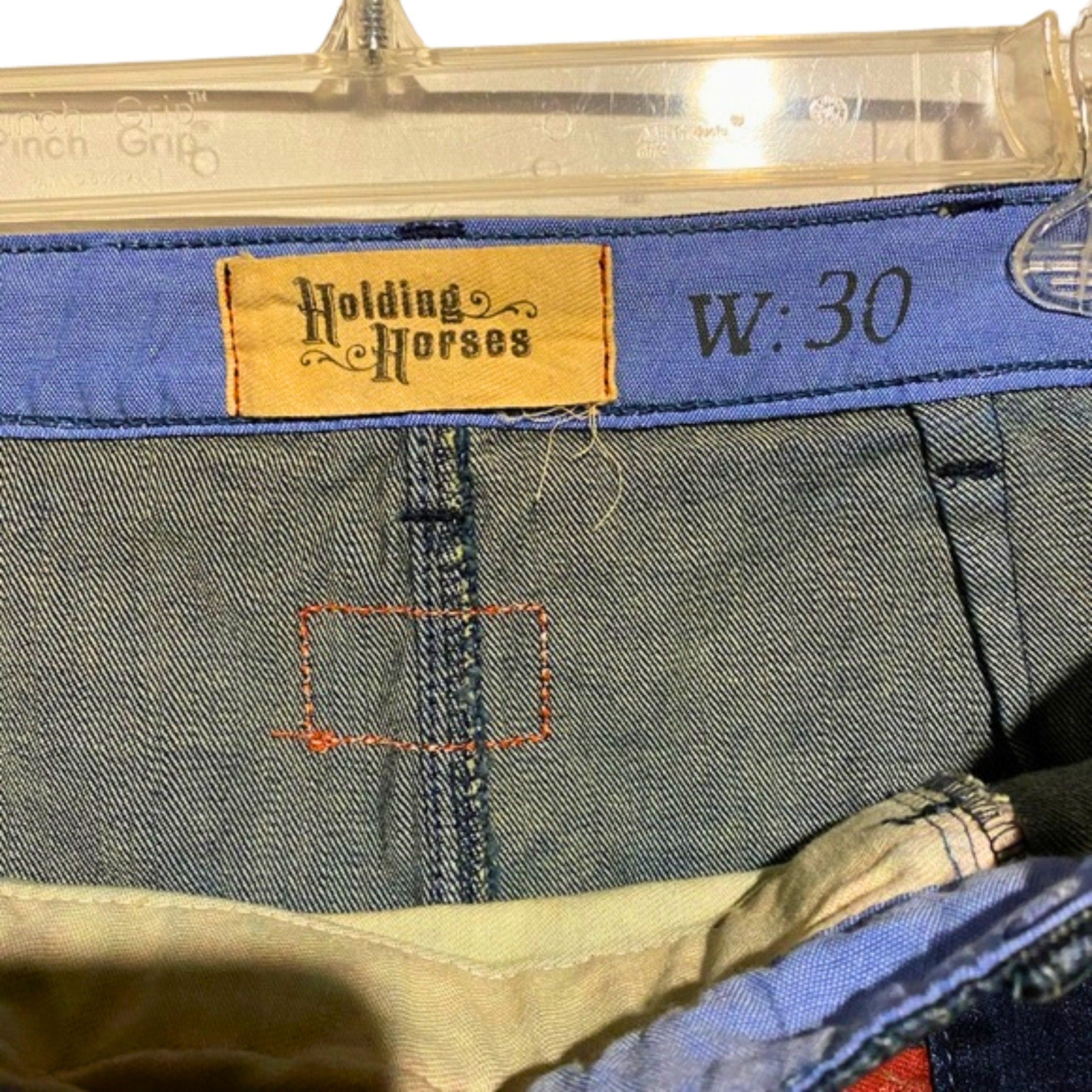 Close-up of jeans with a 'Holding Horses' label and waist size 30.
