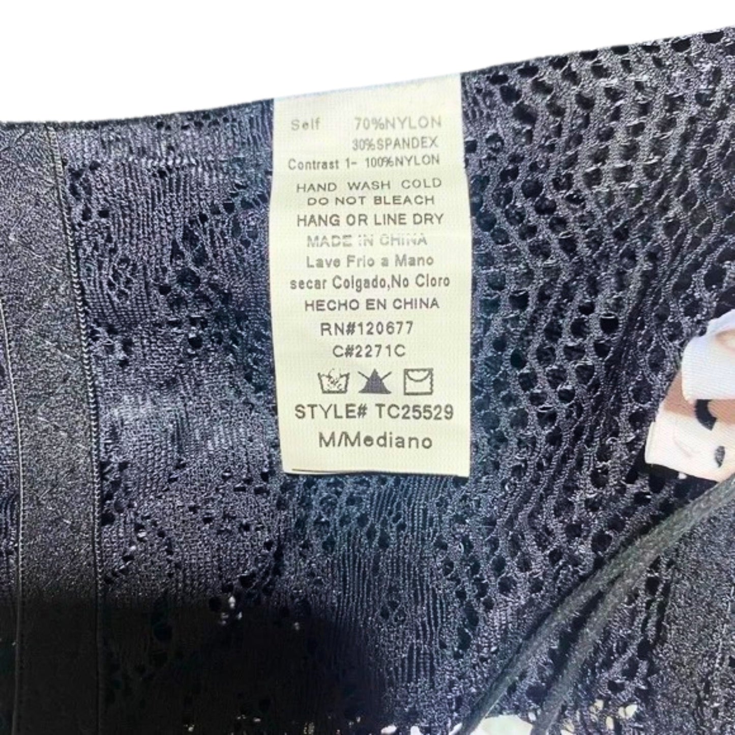 Close-up of a label on a piece of black lace fabric with text and symbols.
