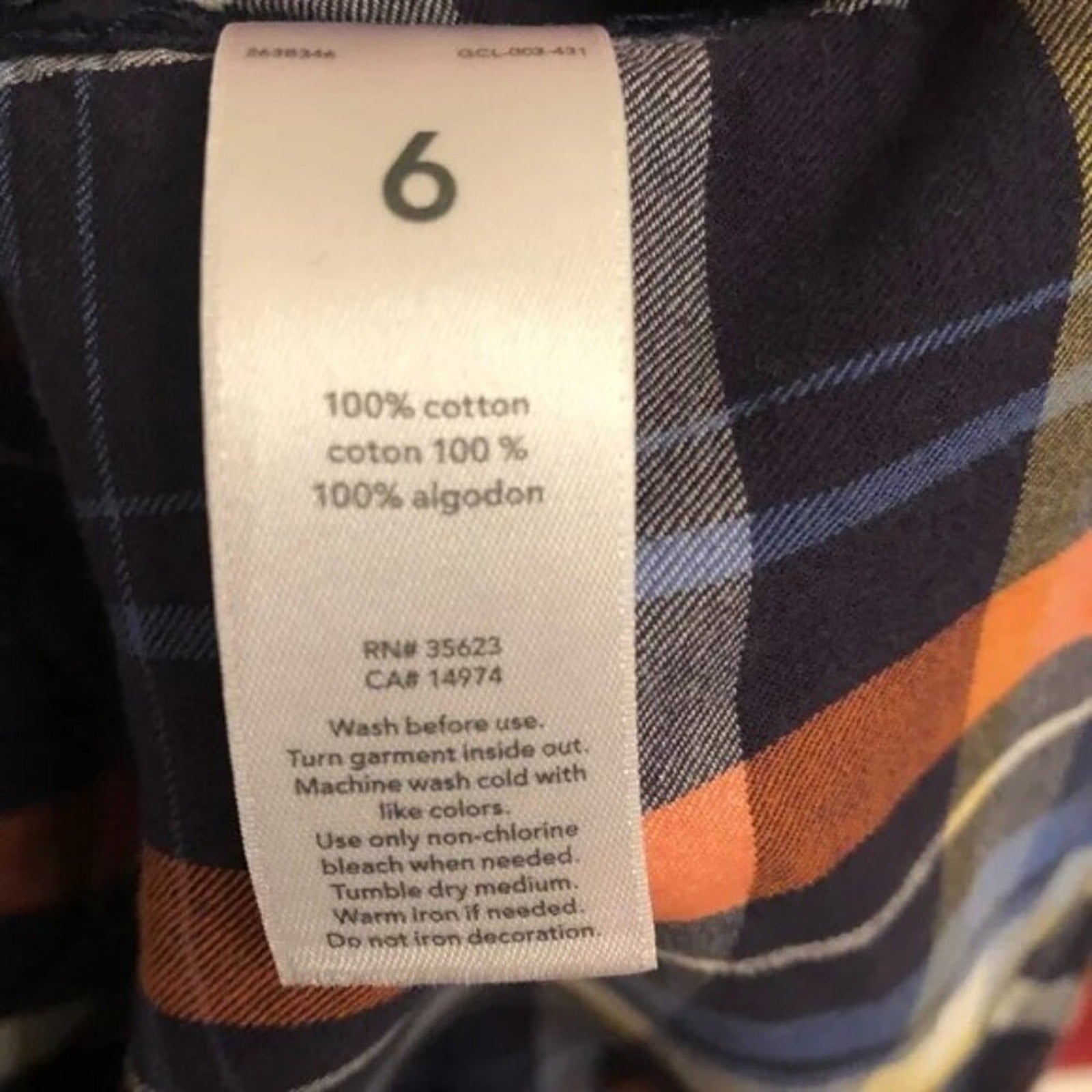 Clothing label on a plaid garment with text and numbers.