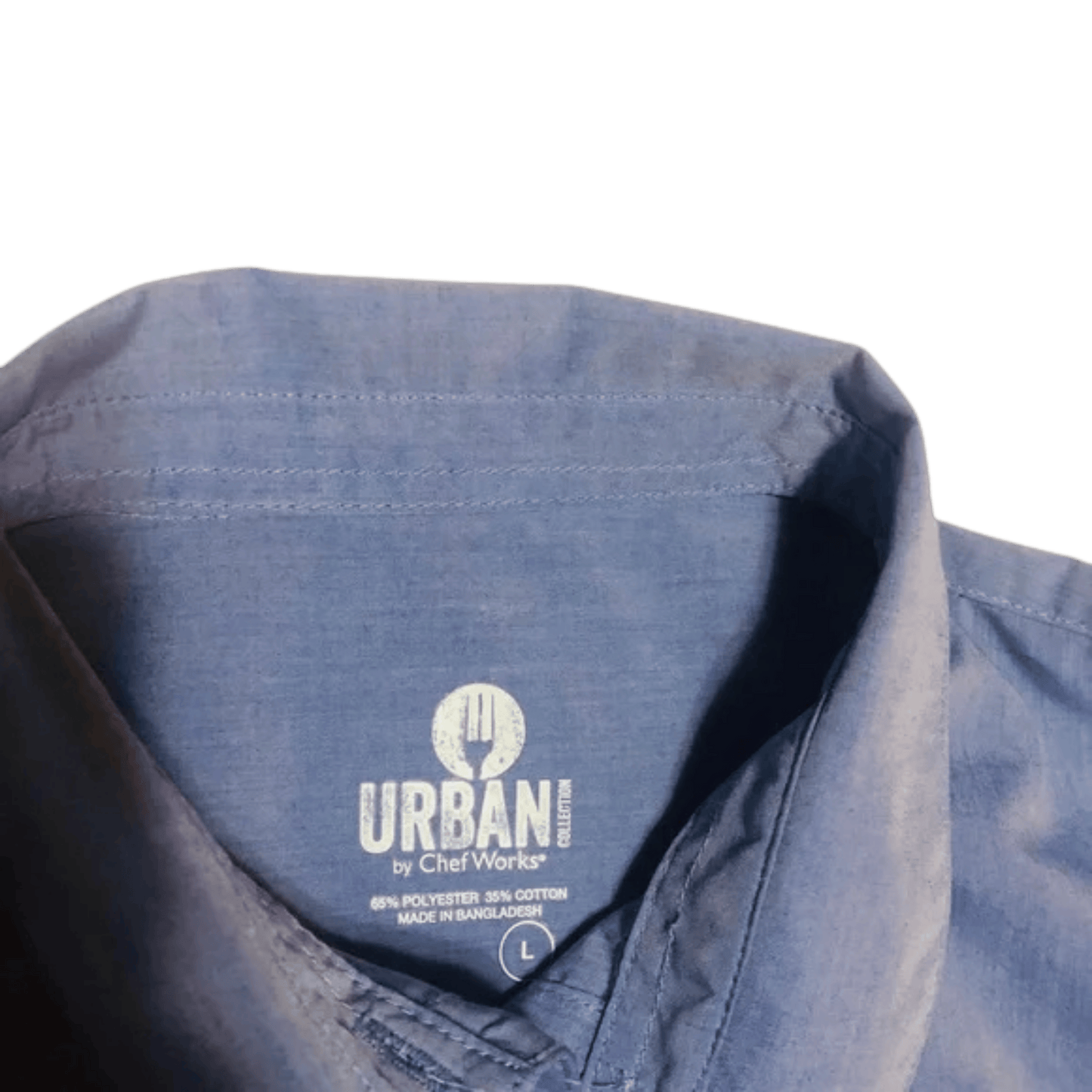 Close-up of a blue shirt with 'Urban by Chef Works' label on a green background