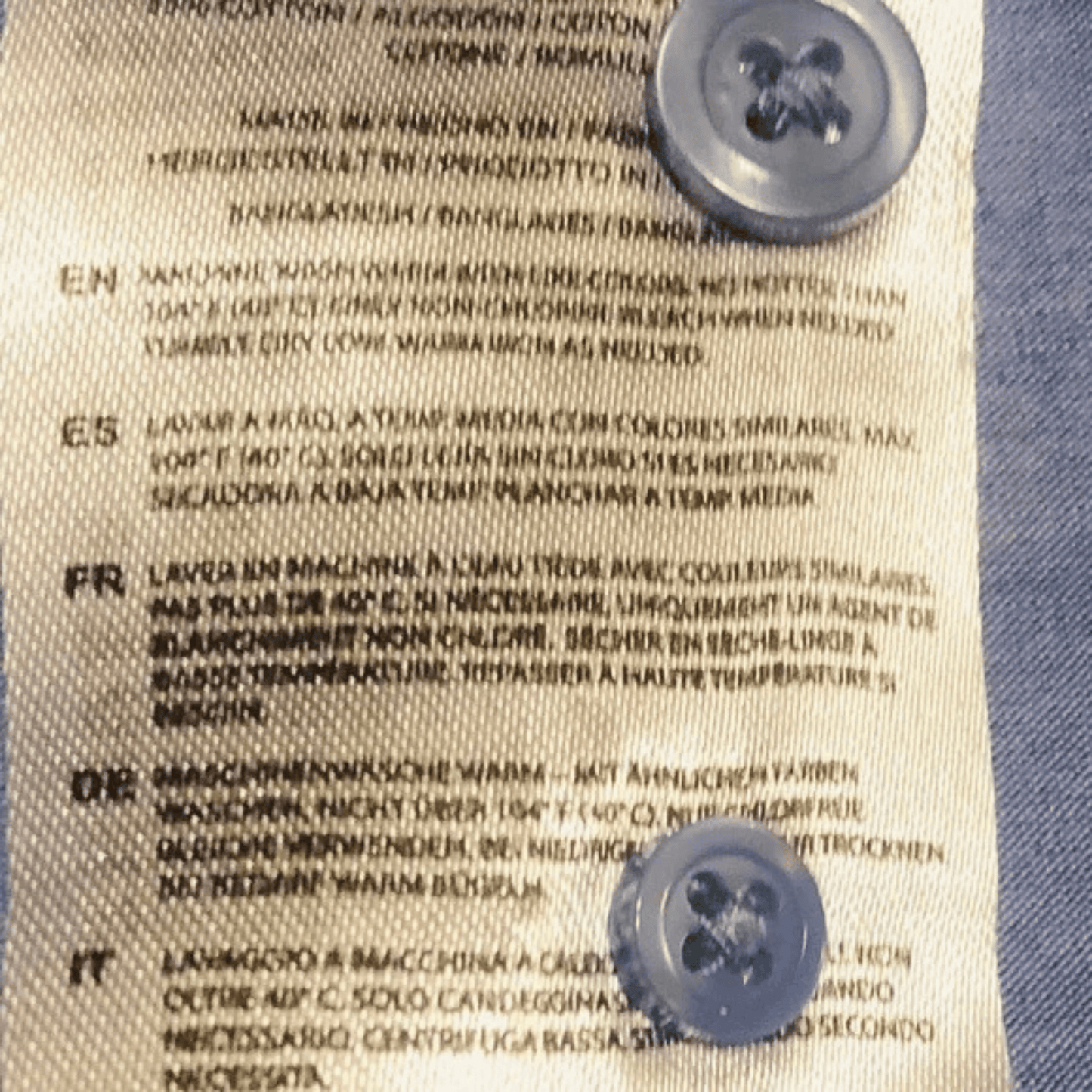Text on a fabric label with two buttons on a blue and beige background