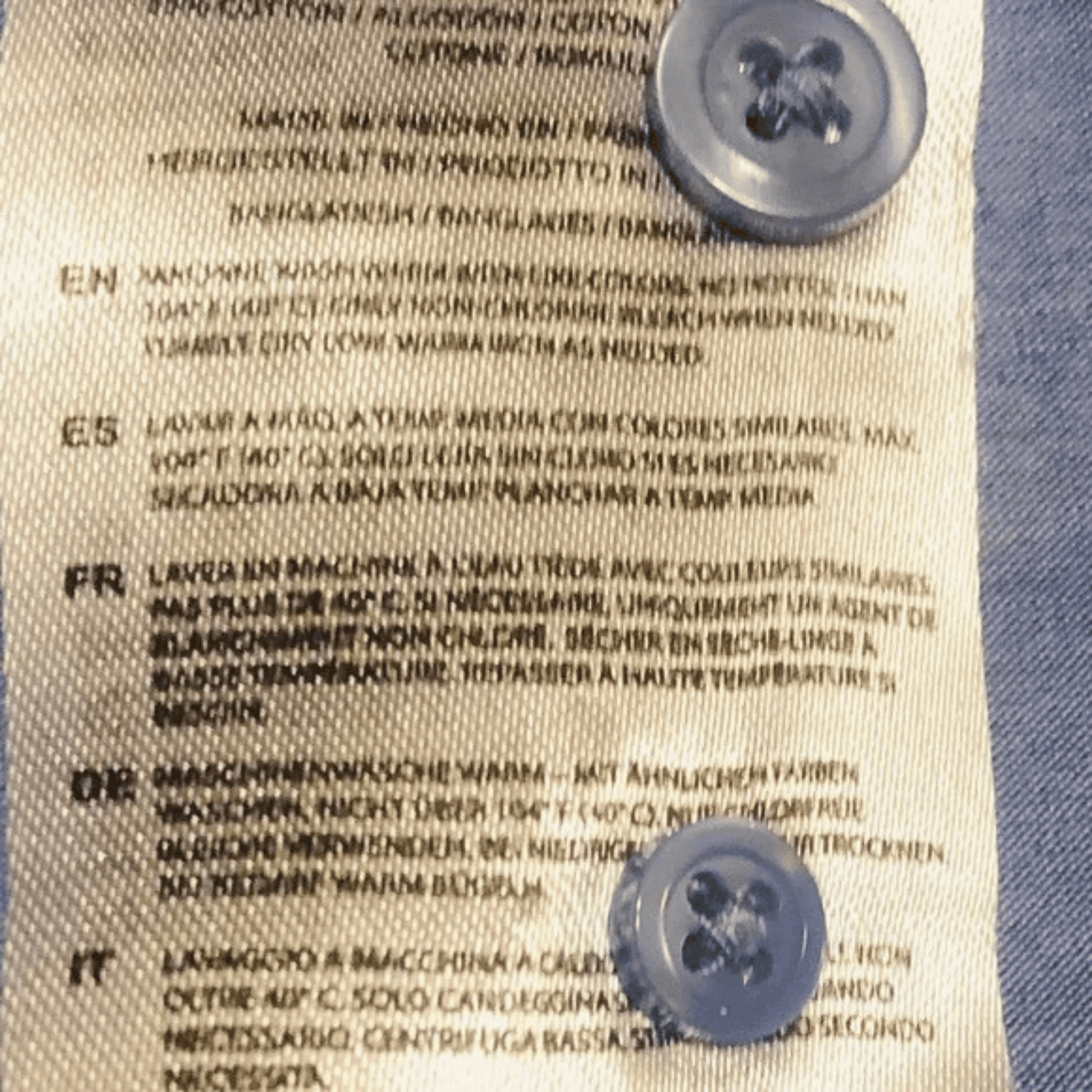 Text on a fabric label with two buttons on a blue and beige background