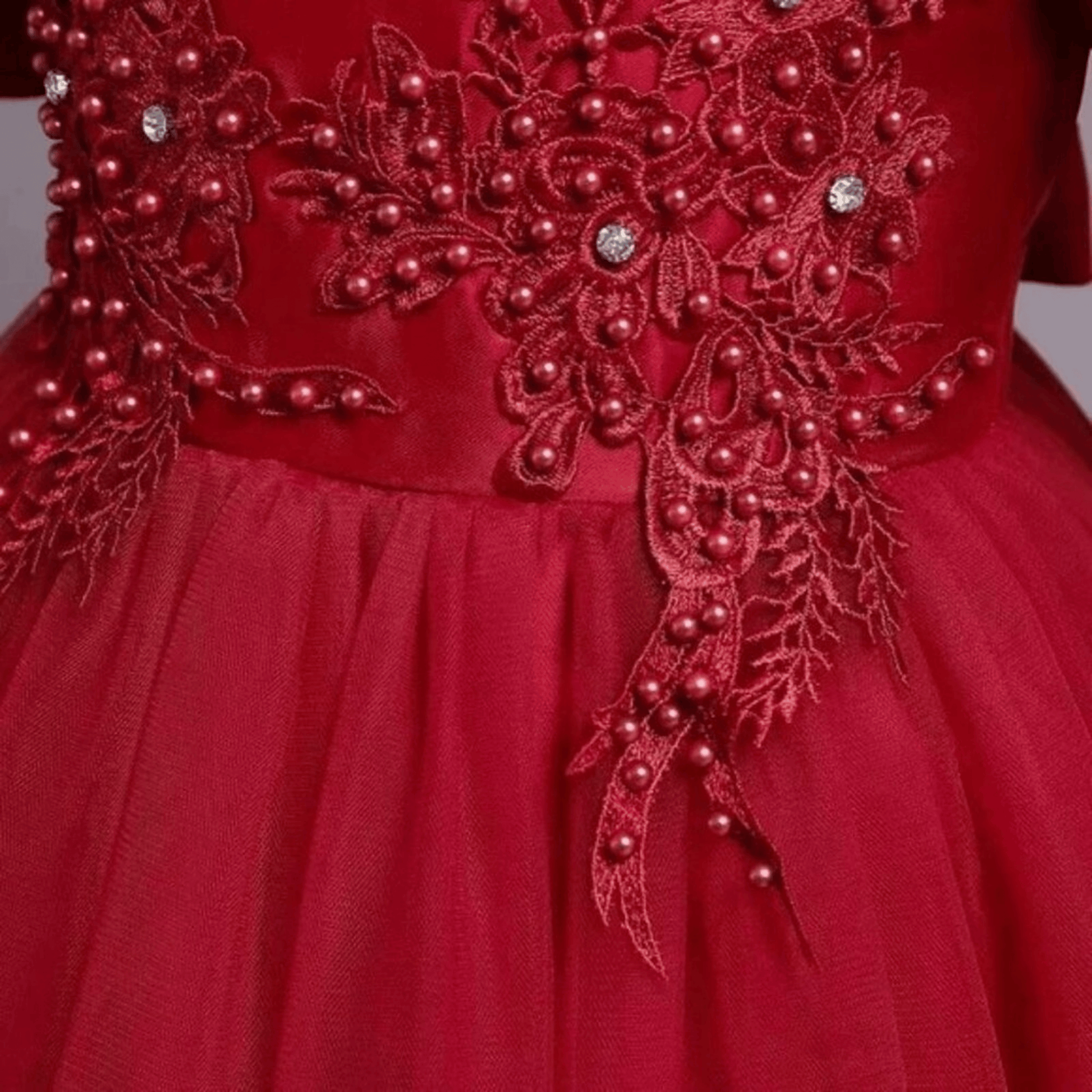 Red dress with intricate beadwork and floral patterns on a plain background
