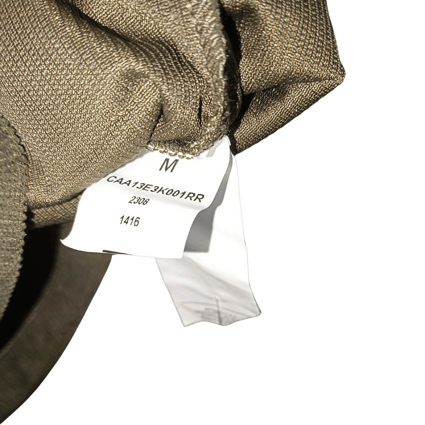 Close-up of a brown fabric with a white tag displaying text and a size label on a green background.