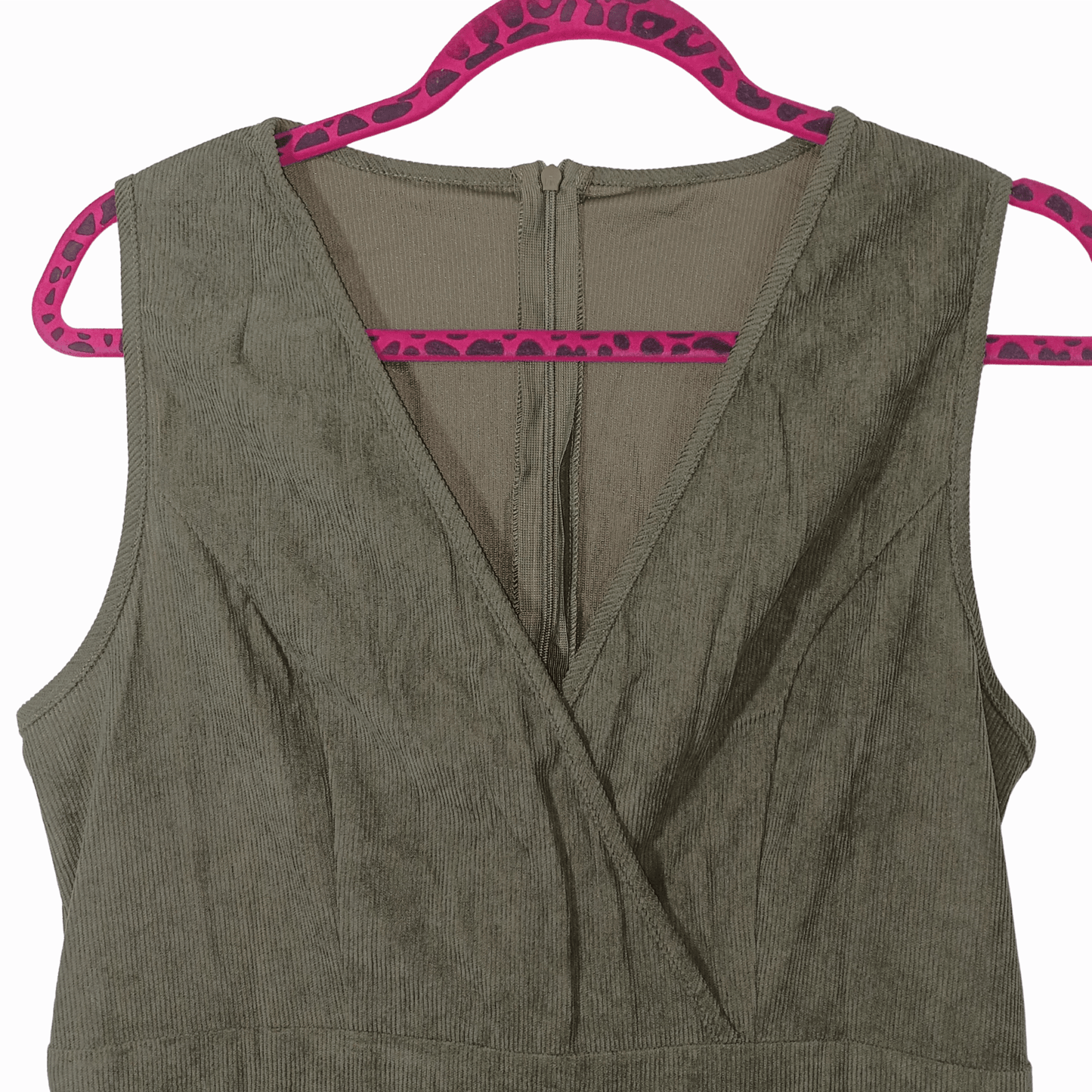 Green sleeveless top on a pink hanger against a pink background