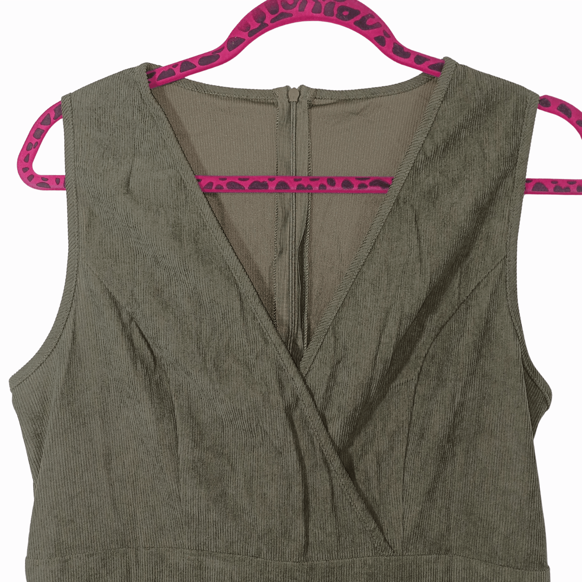 Green sleeveless top on a pink hanger against a pink background