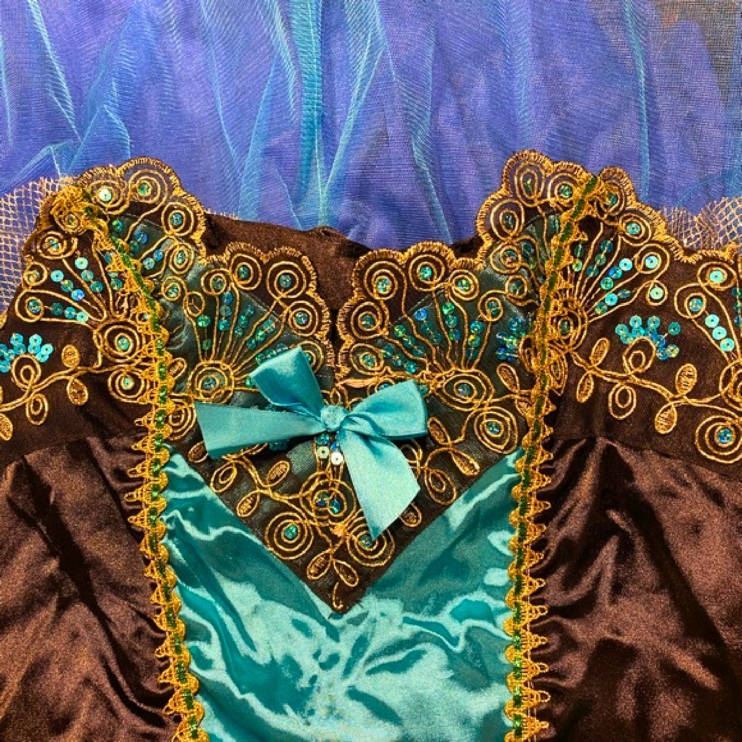Decorative headband with gold embroidery and a blue bow on a blue and brown fabric background