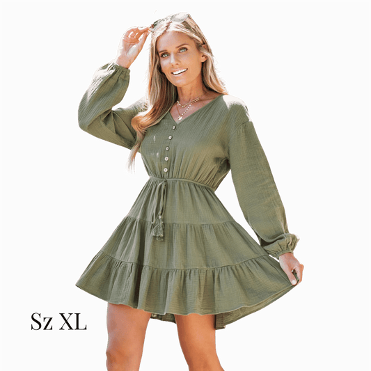 Woman wearing a green dress with long sleeves on a gray background