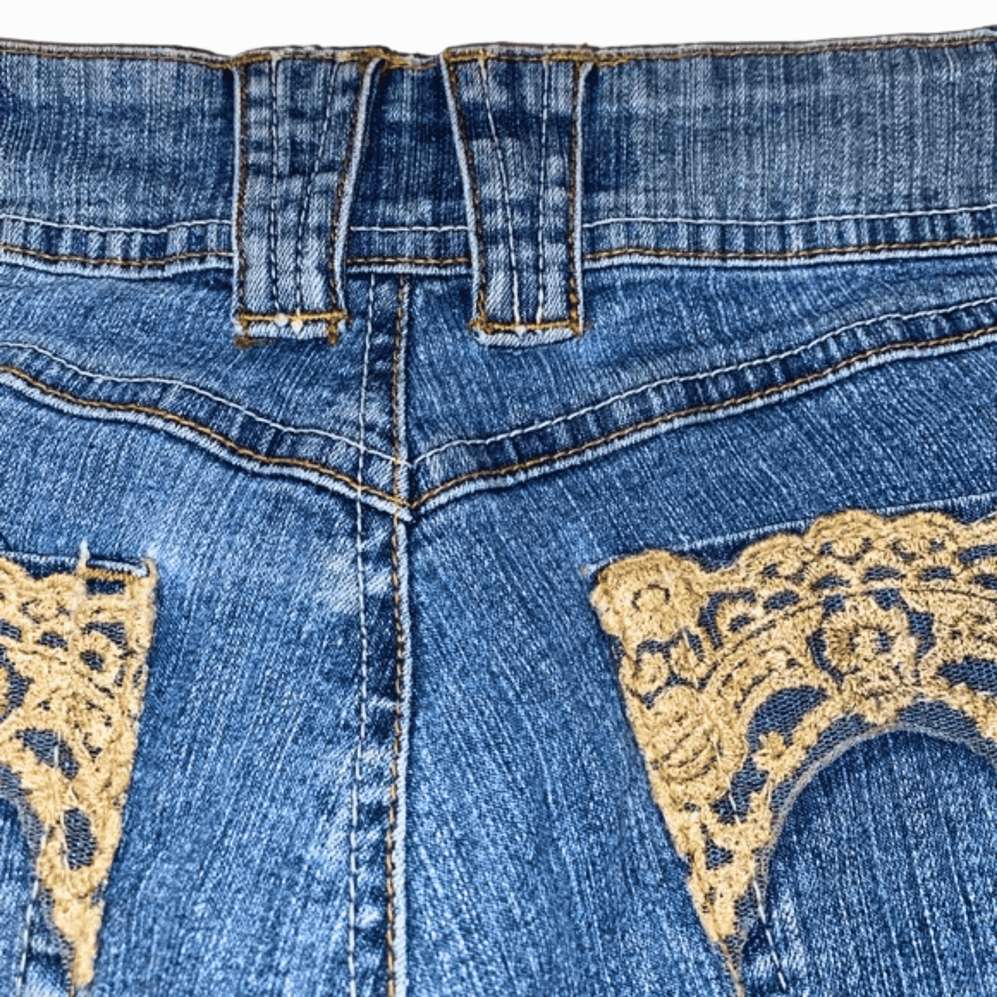 Blue jeans with gold lace detailing on a gray background
