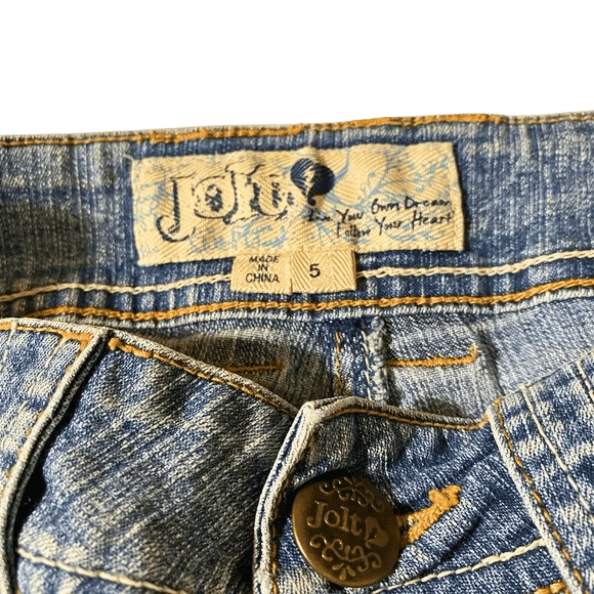 Close-up of a denim garment with a brand label and button.