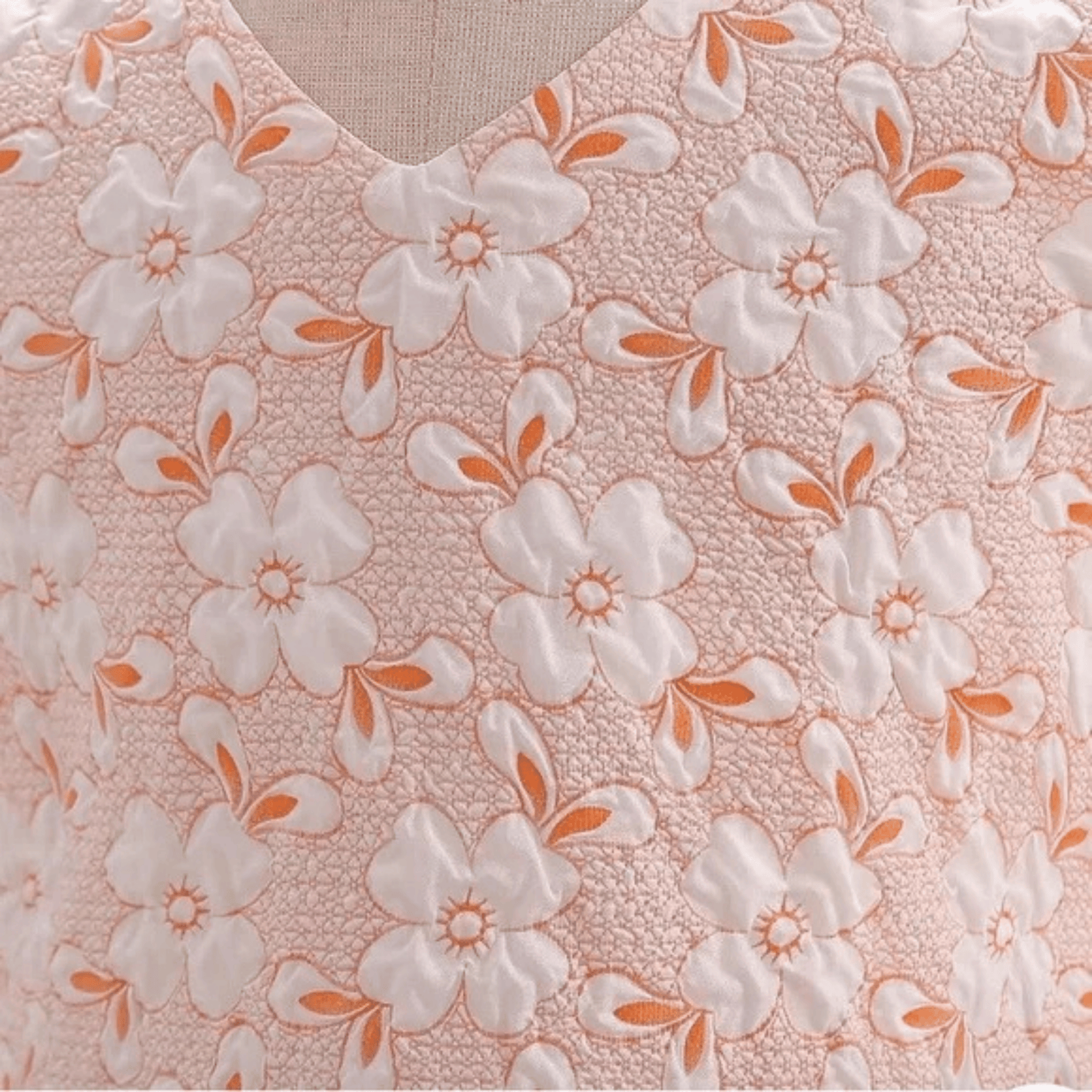 Floral patterned fabric with white flowers and orange accents on a pink background