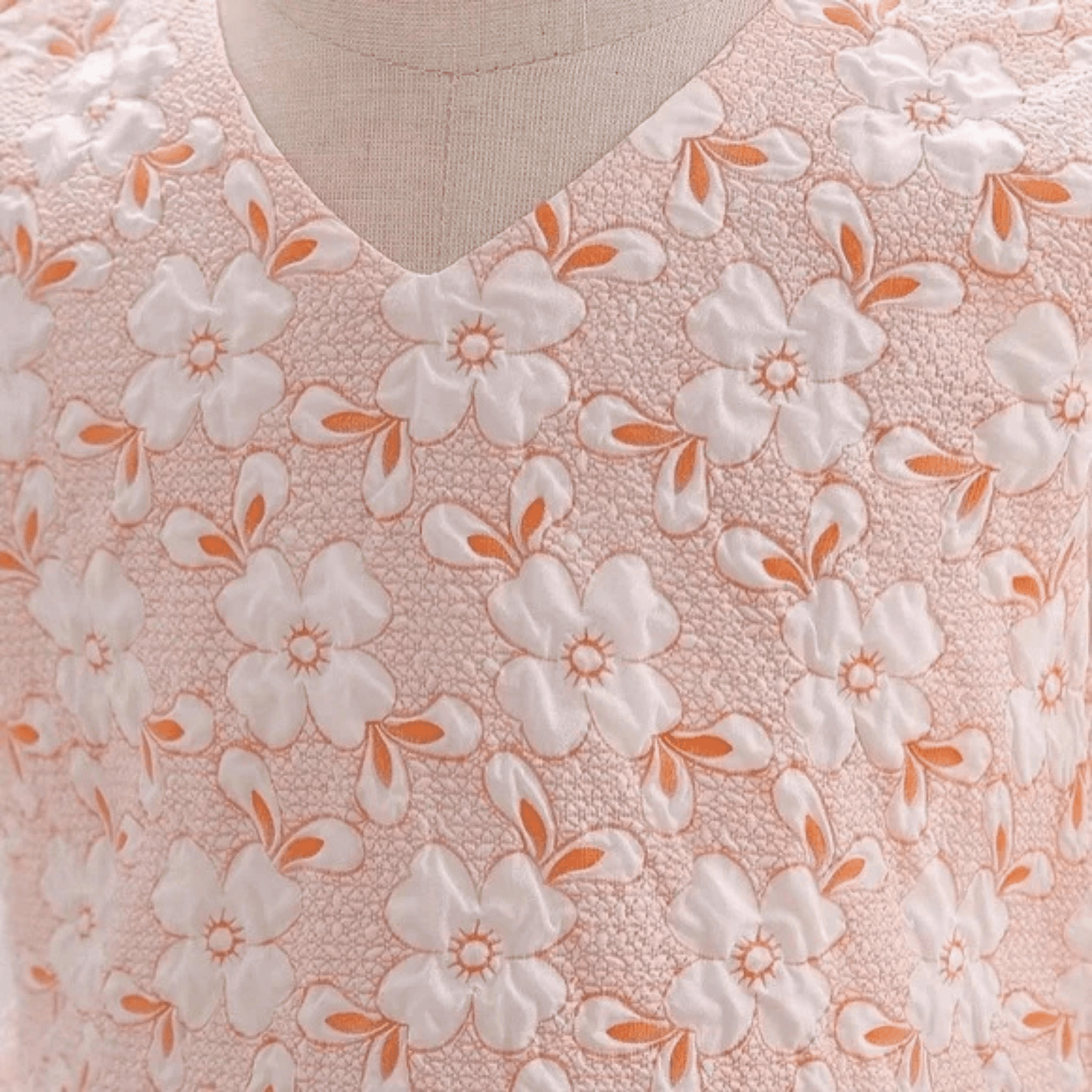 Floral patterned fabric with white flowers and orange centers on a pink background