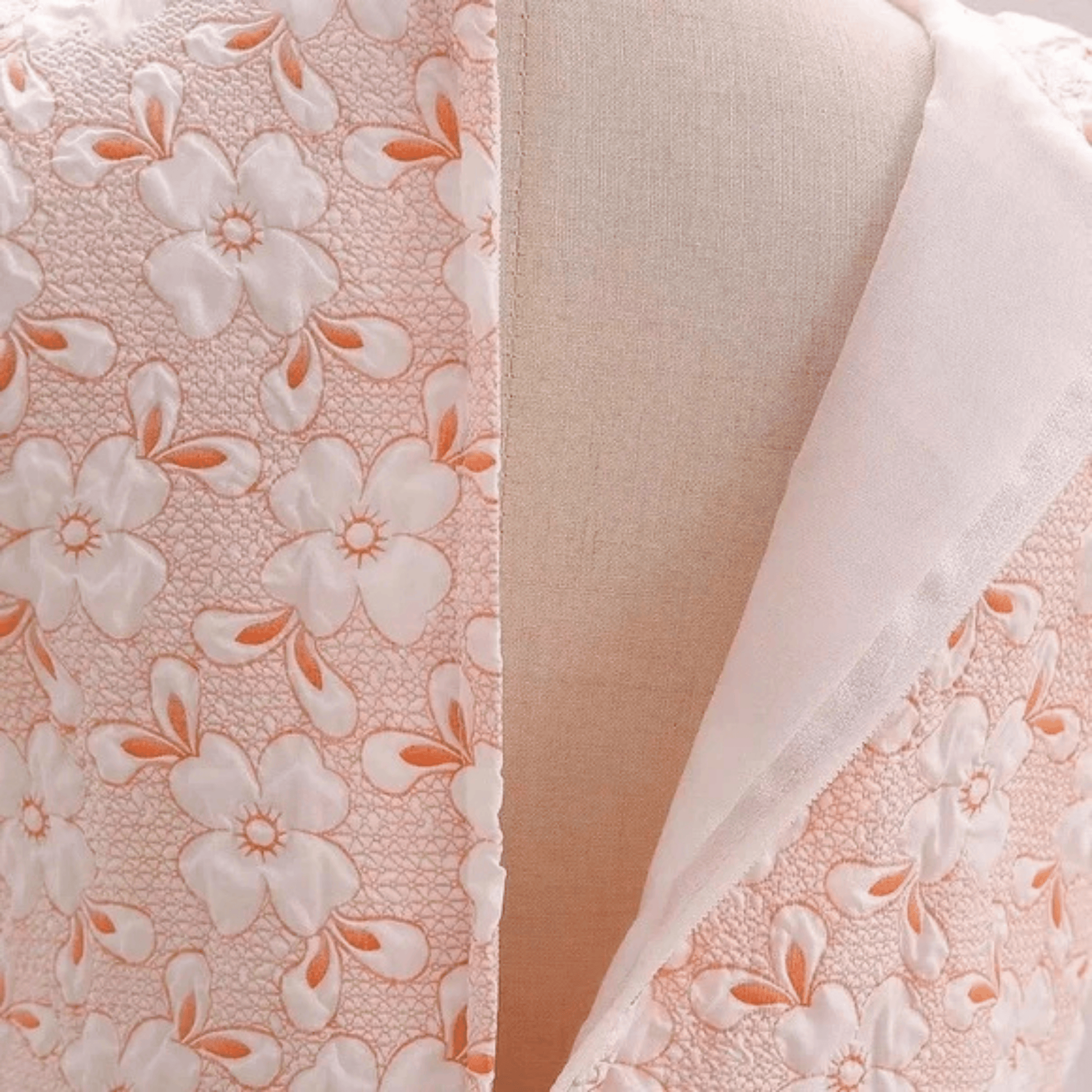 Close-up of floral fabric with white flowers and orange centers on a pink background.
