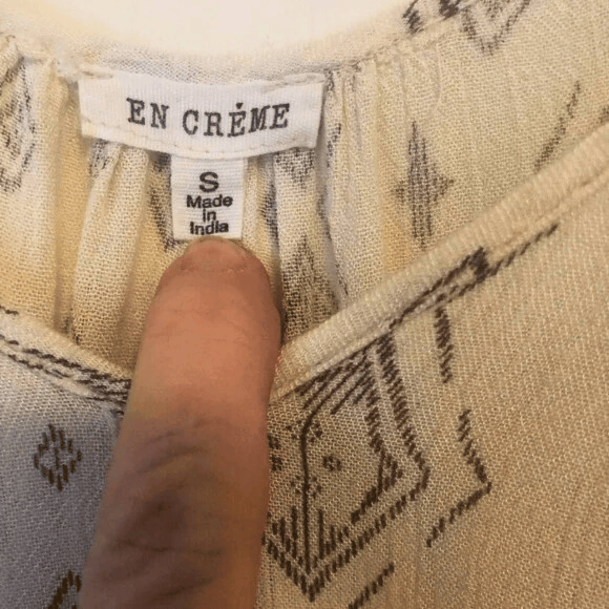Close-up of a fabric label with 'EN CREME' branding and size information.