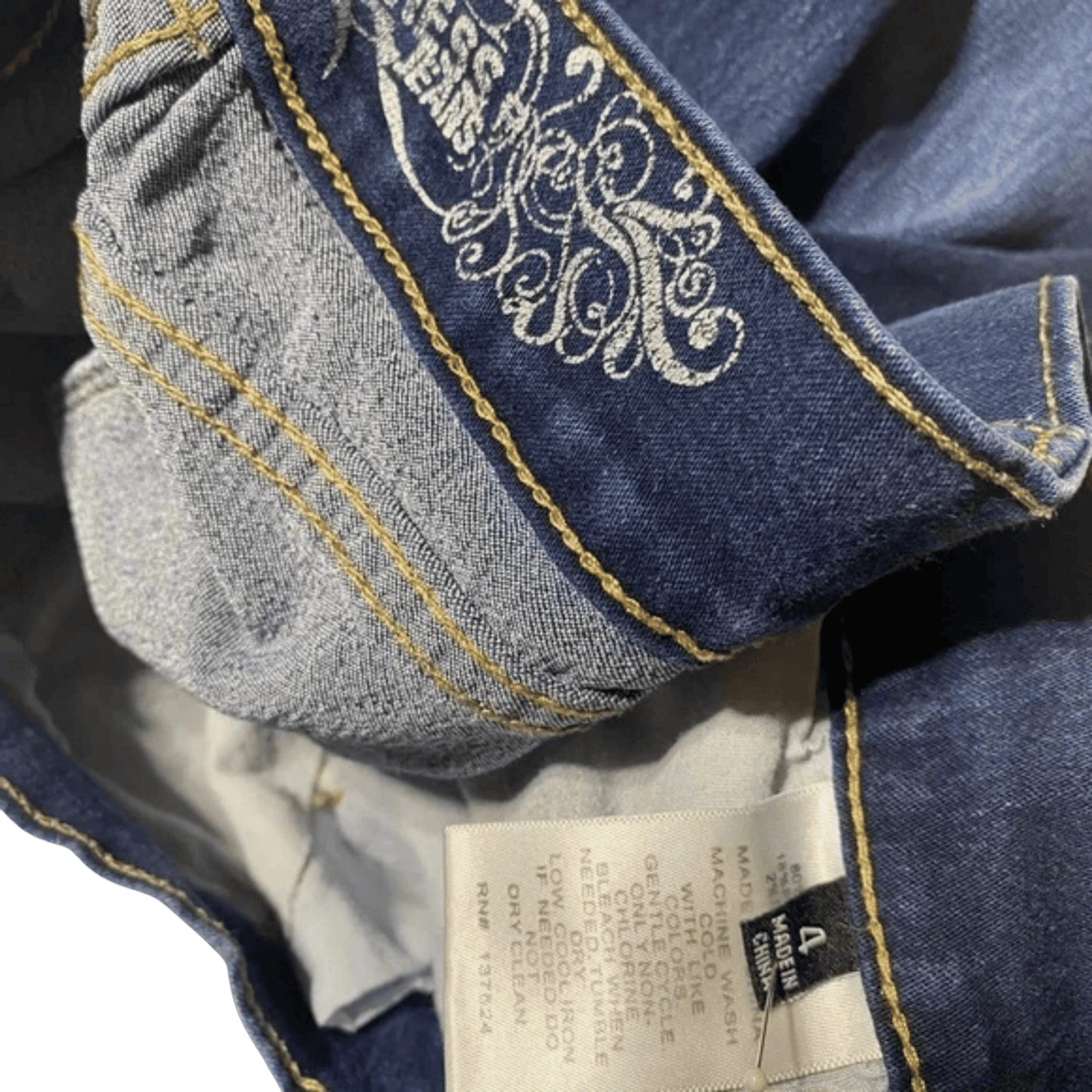 Close-up of blue jeans with decorative stitching and a brand label.