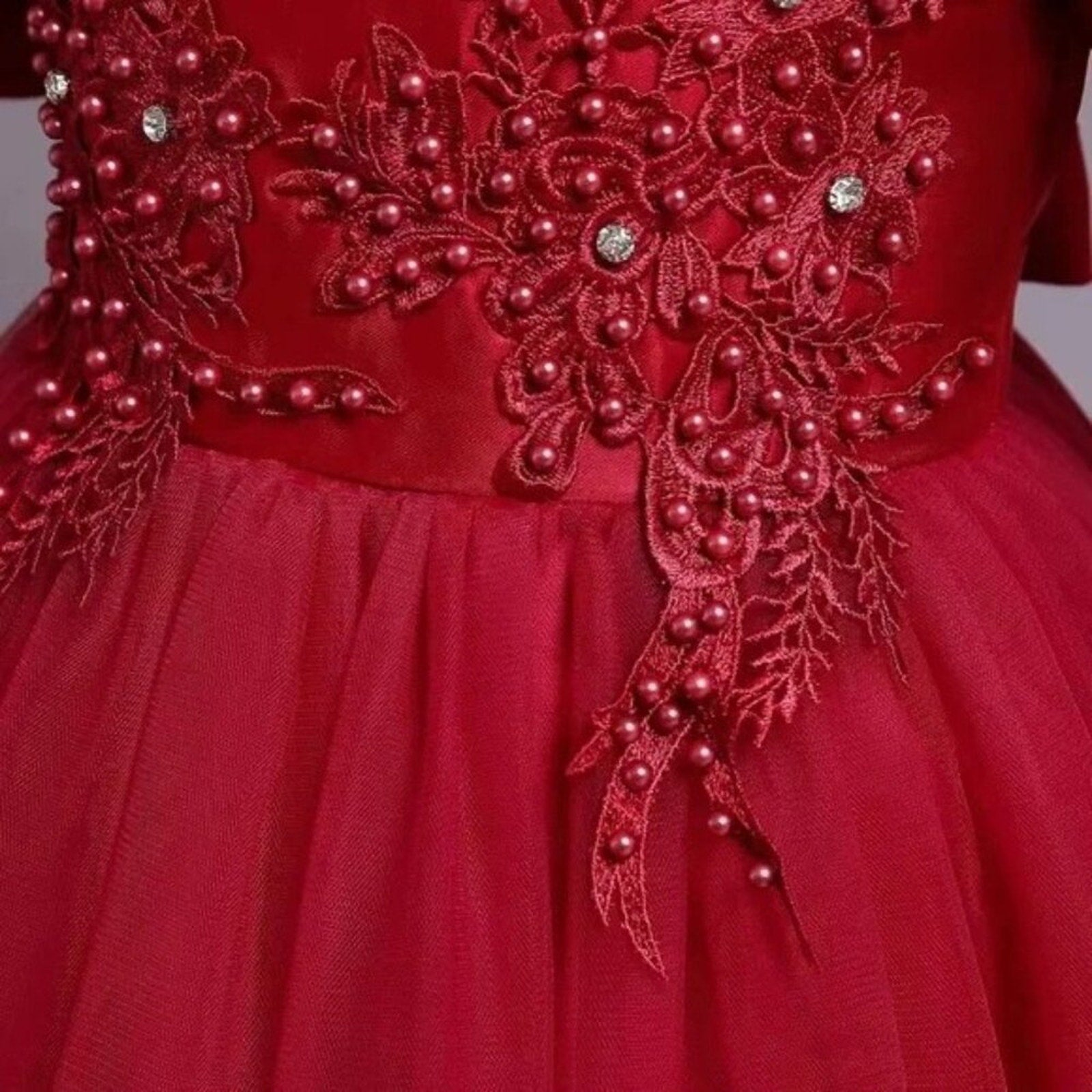 Red dress with pearl embellishments on a plain background