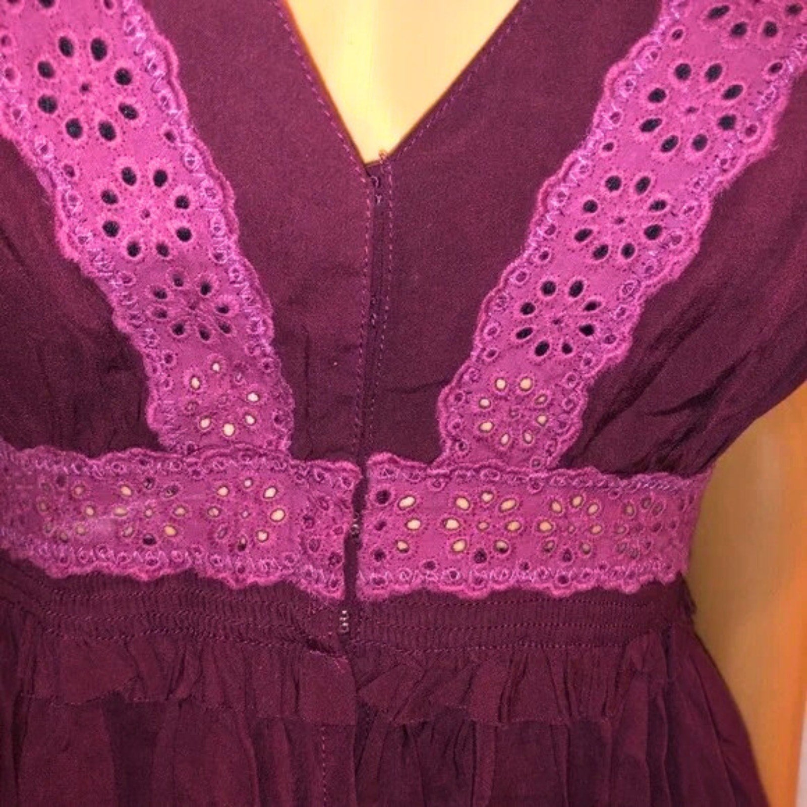 Close-up of a purple dress with intricate lace detailing on a mannequin.