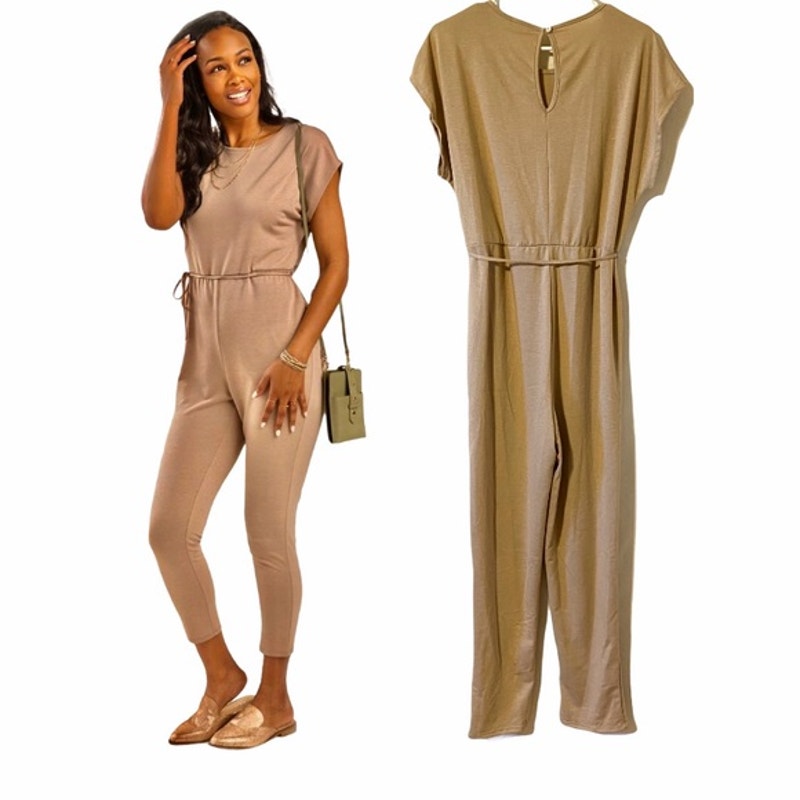 Woman wearing a beige jumpsuit with a plain background