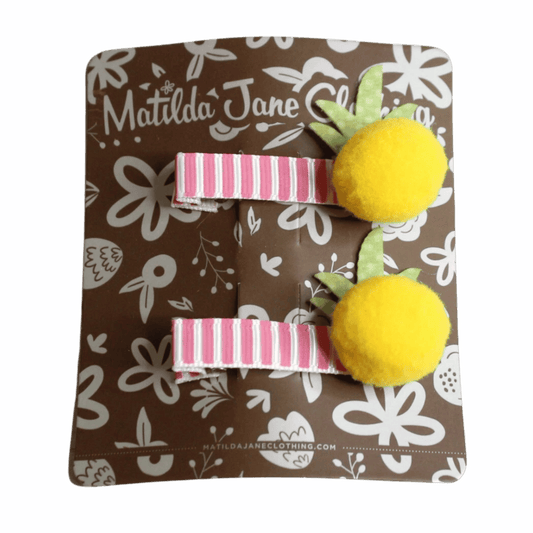 Two hair clips with yellow pom-poms and pink stripes on a Matilda Jane Clothing branded card.