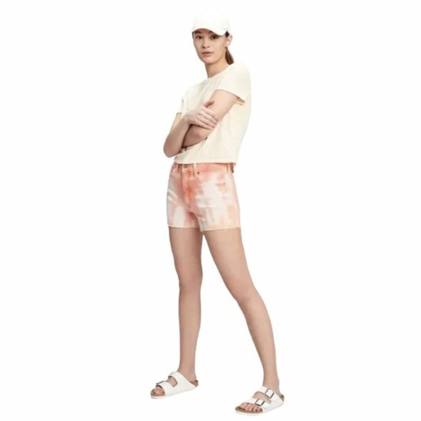 Woman wearing a light-colored t-shirt and tie-dye shorts on a white background