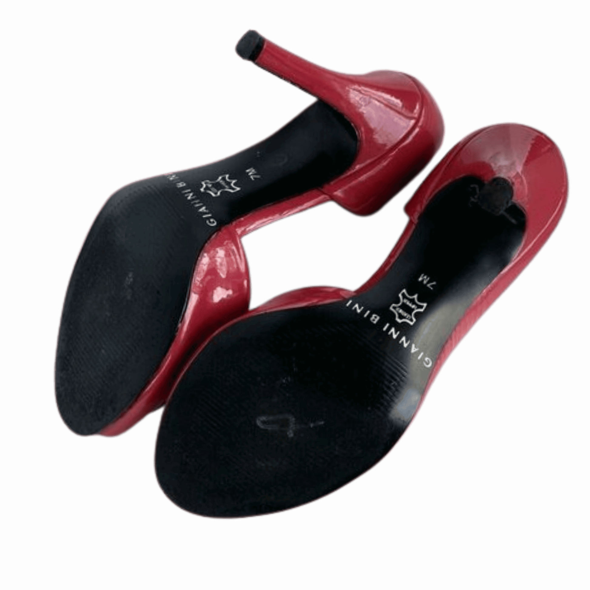 Red high-heeled shoes with black soles on a green background