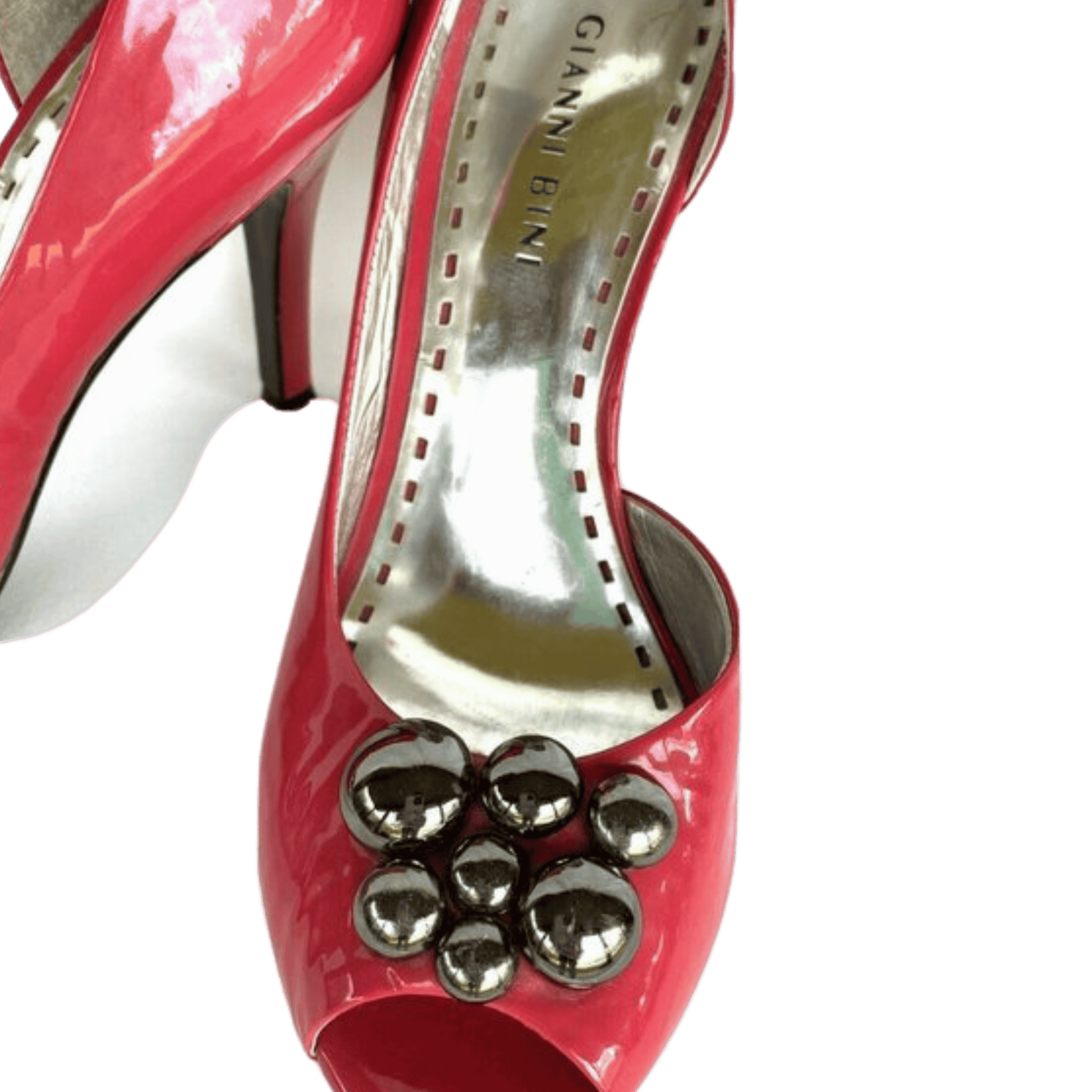 Red high-heeled shoe with silver embellishments on a green background