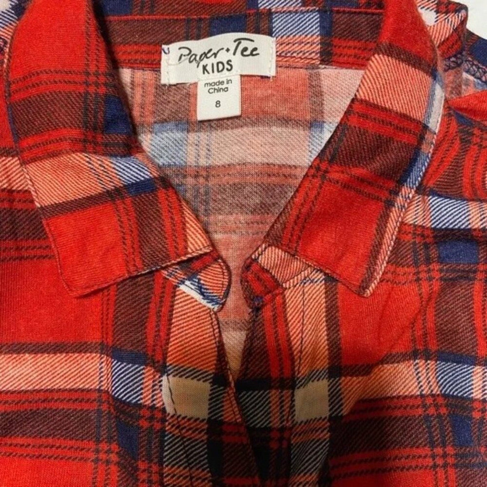 Red plaid shirt with a 'Paper Tee Kids' tag on a close-up of the collar.