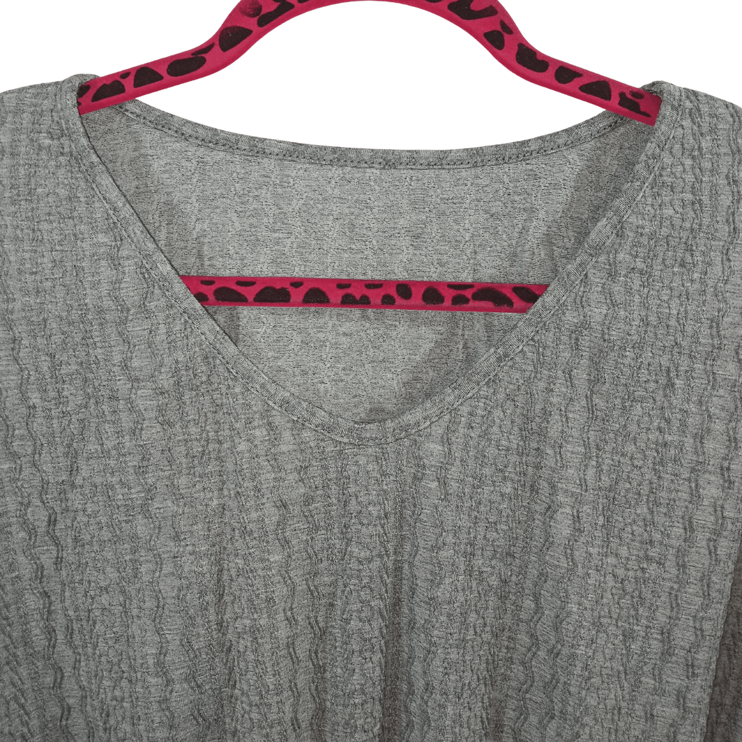Gray shirt with red and black patterned trim on a hanger against a green background