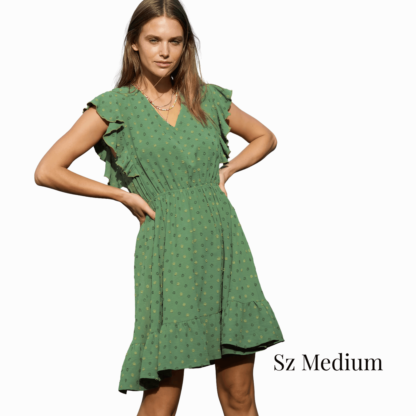 Woman wearing a green dress with ruffled sleeves on a gray background