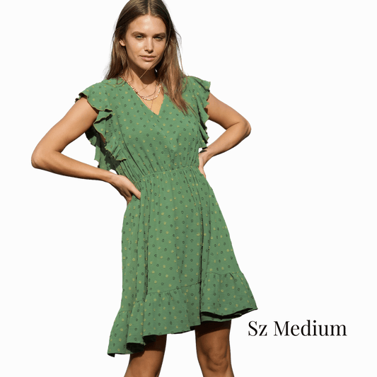 Woman wearing a green dress with ruffled sleeves on a gray background
