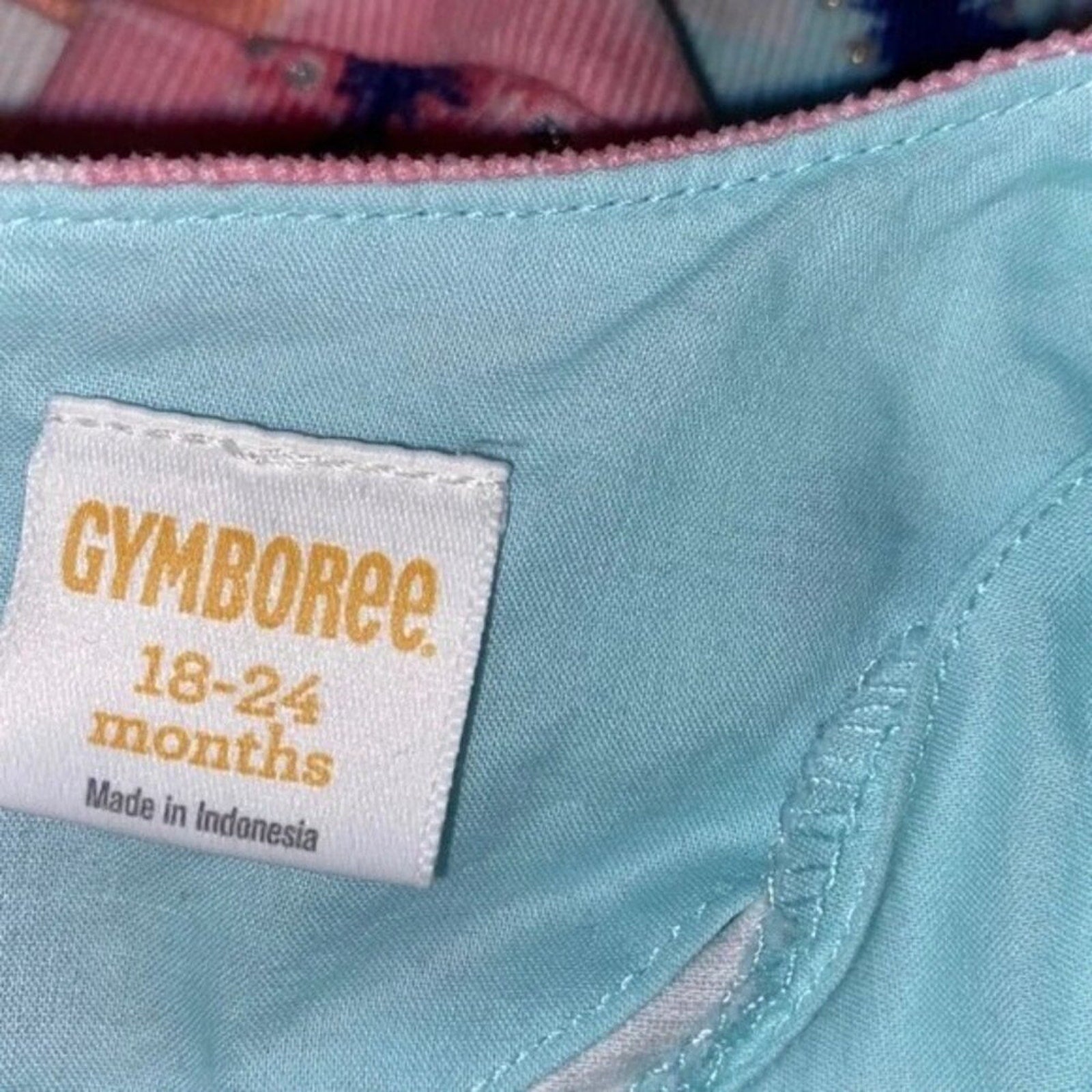 Gymboree label on a light blue fabric with pink zipper in the background