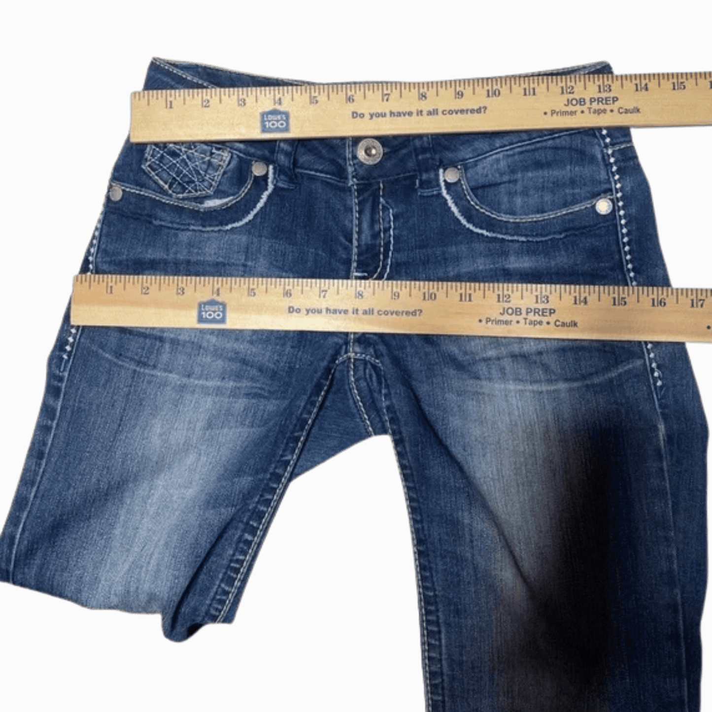 Blue jeans with a measuring tape showing their length on a gray background