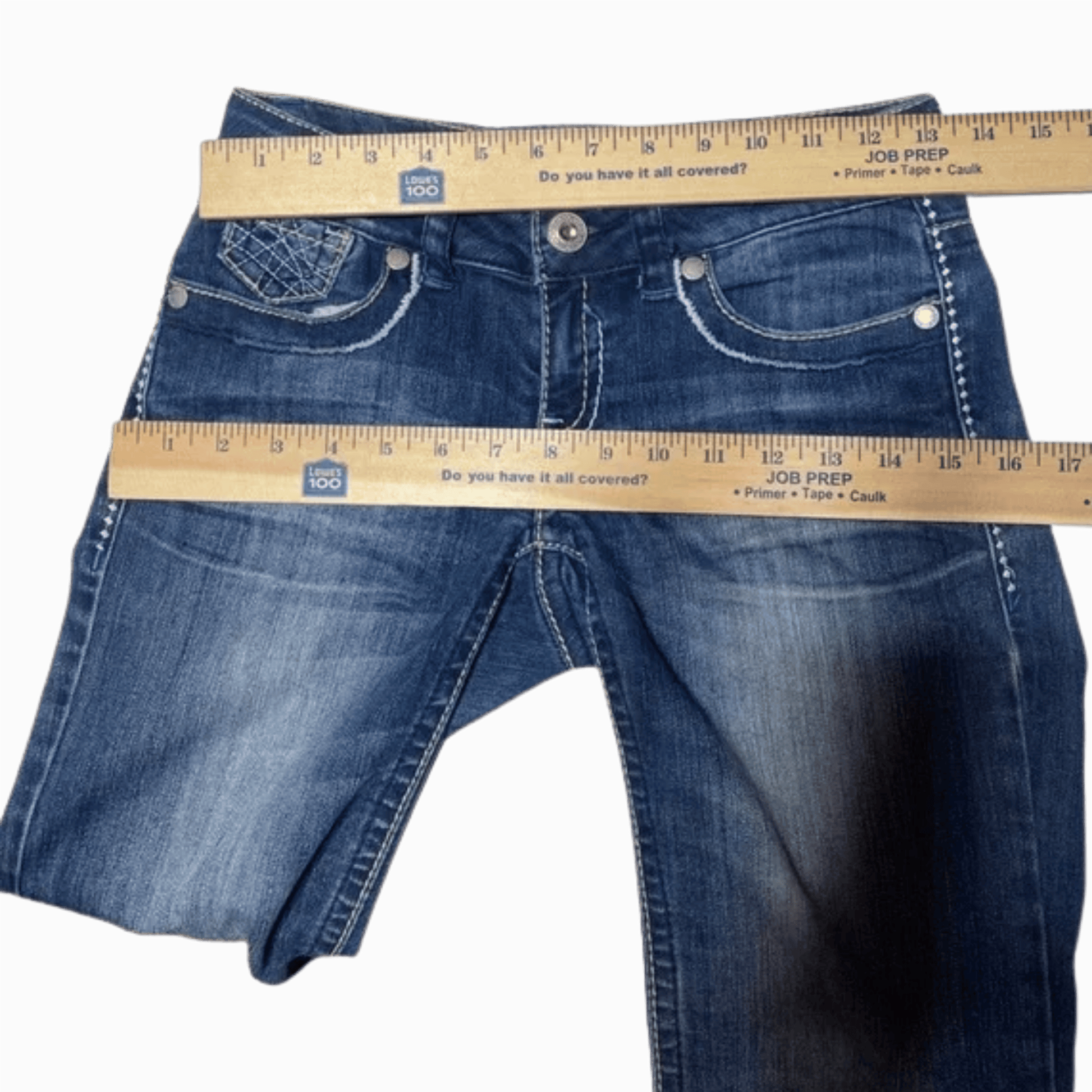 Blue jeans with a measuring tape showing their length on a gray background