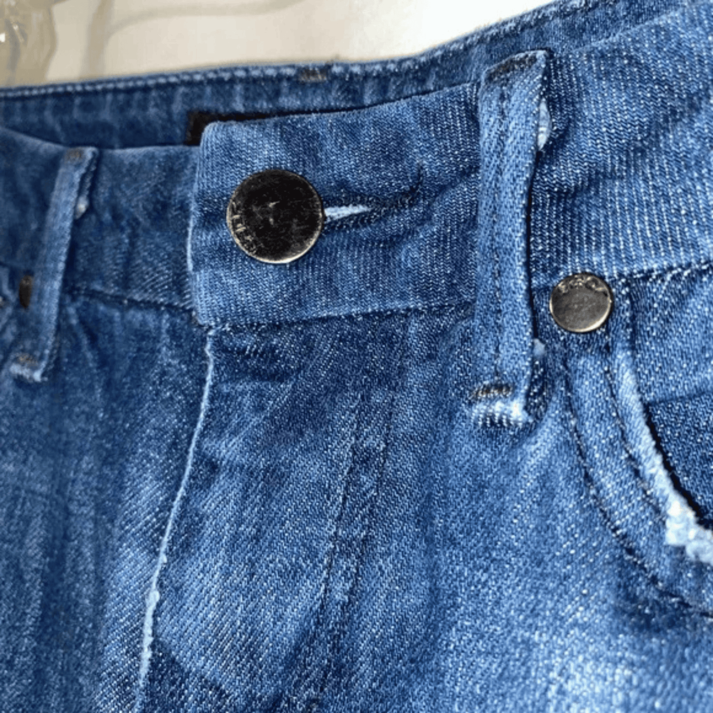 Close-up of blue denim jeans with button and zipper details.