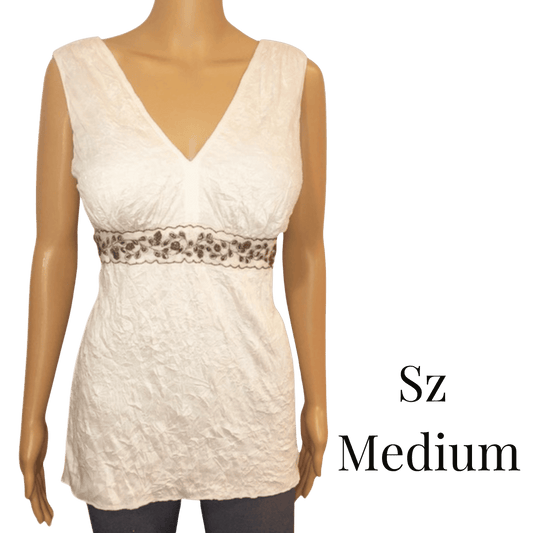 White sleeveless top with leopard print trim on a mannequin against a green background