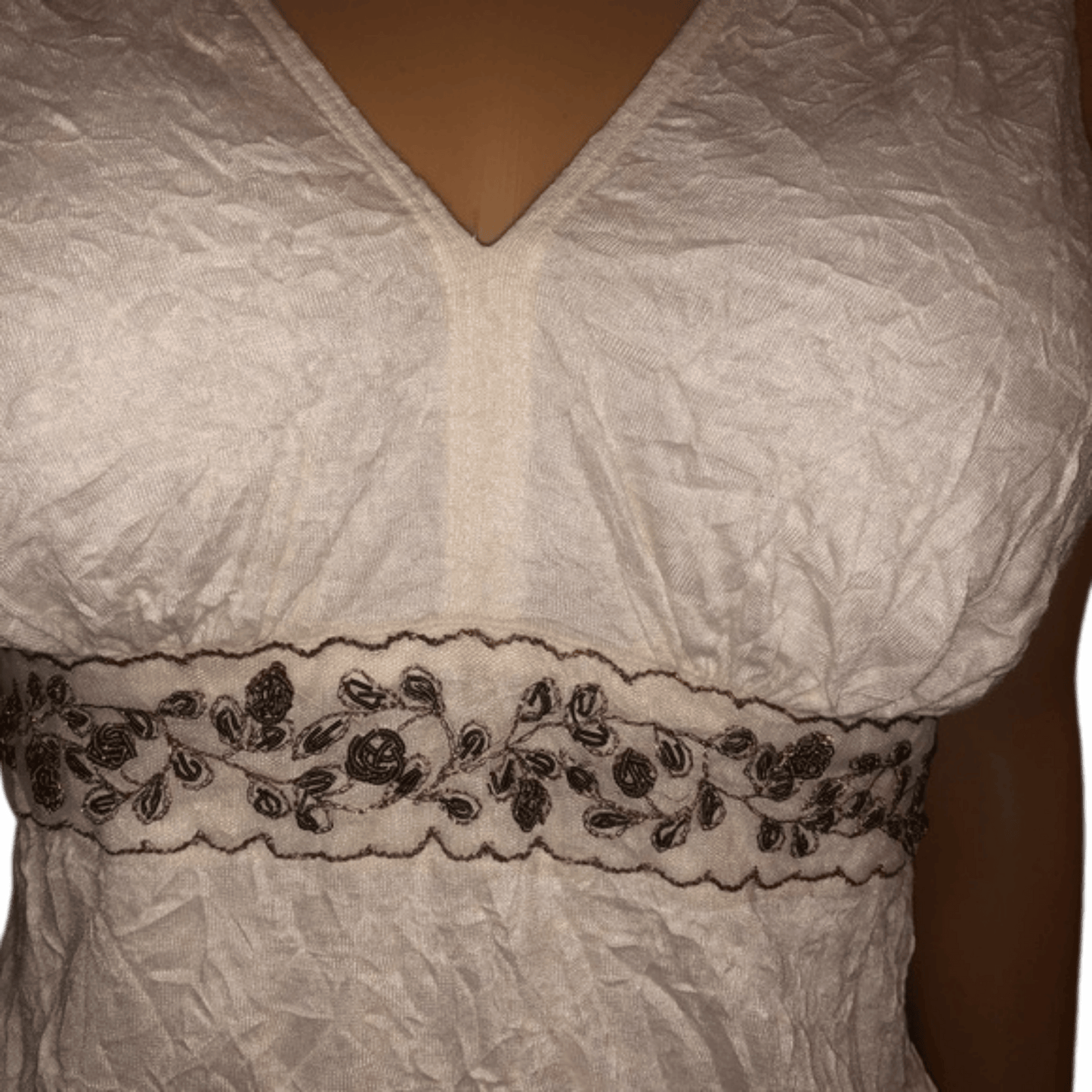 White lace garment with black floral embroidery on a plain background