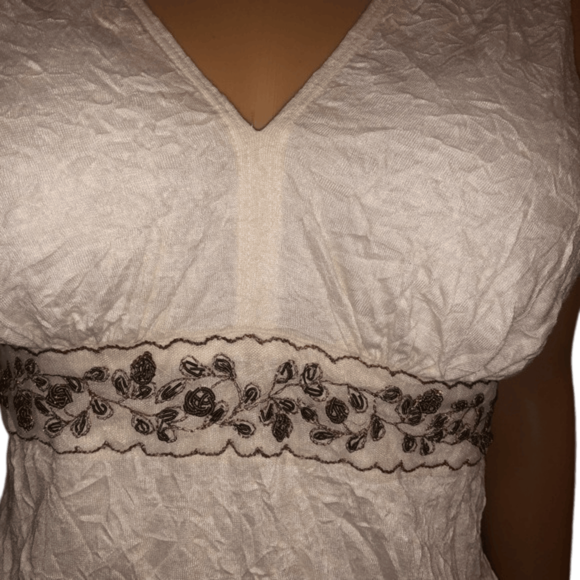 White lace garment with black floral embroidery on a plain background
