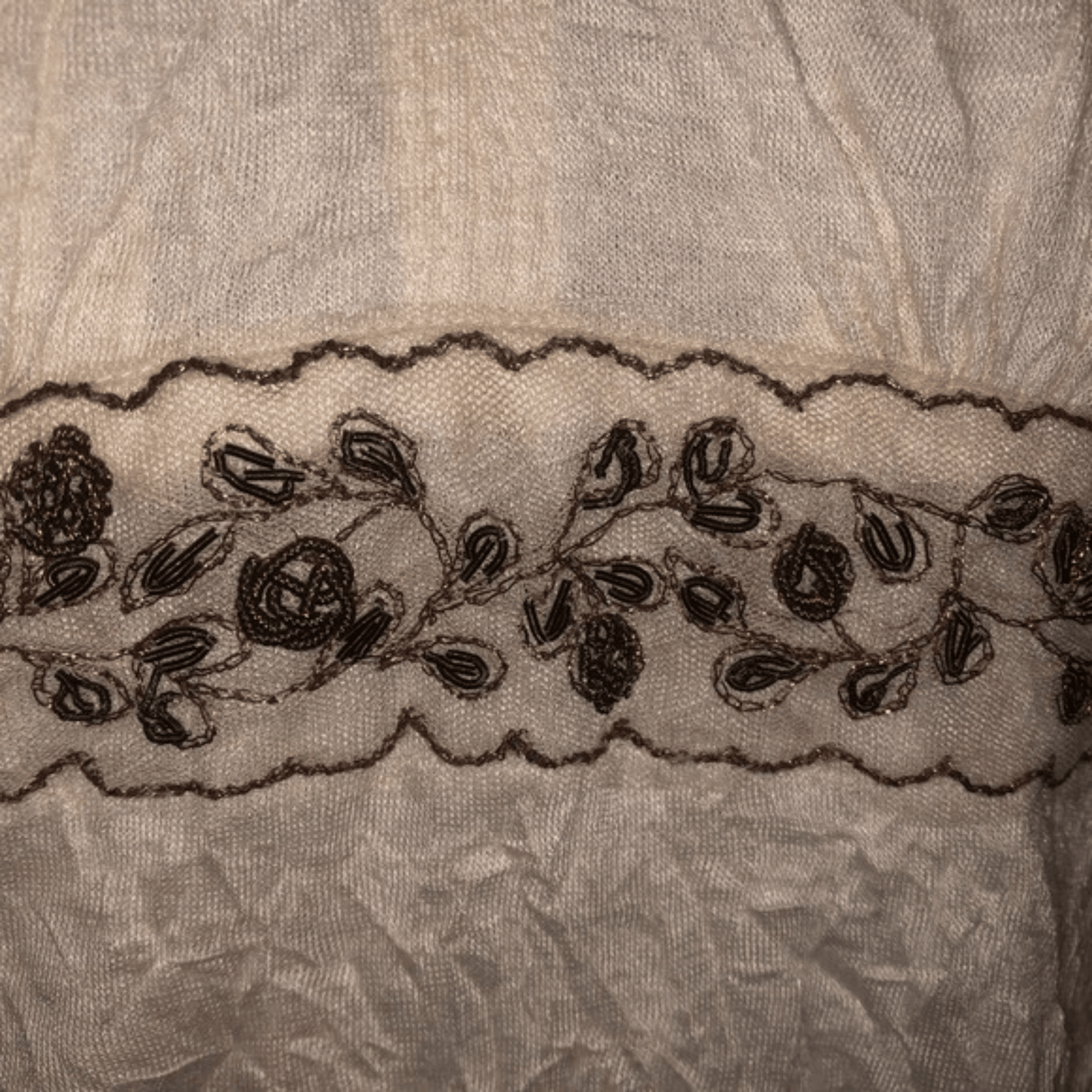 Close-up of a lace trim with floral patterns on a textured fabric background.