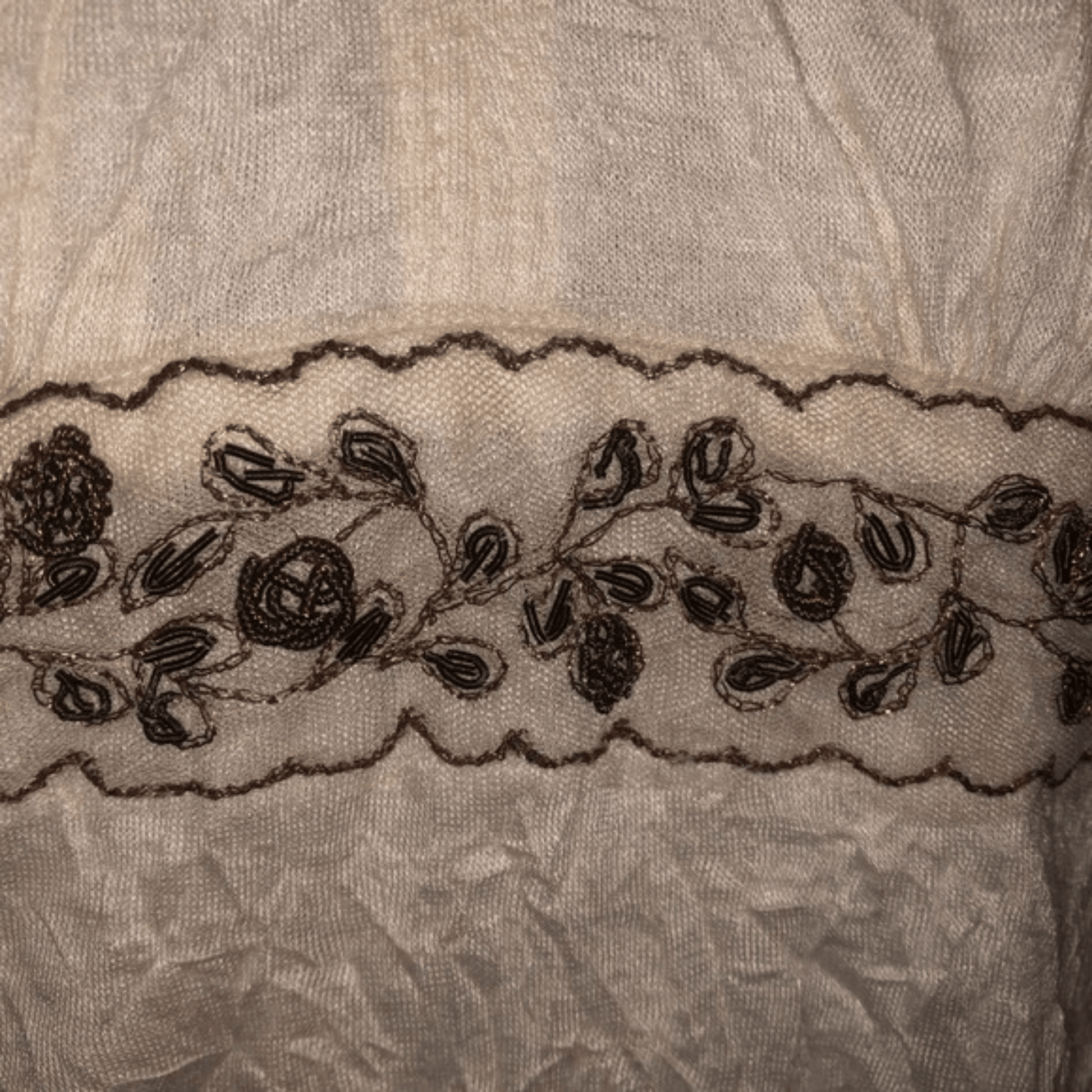 Close-up of a lace trim with floral patterns on a textured fabric background.