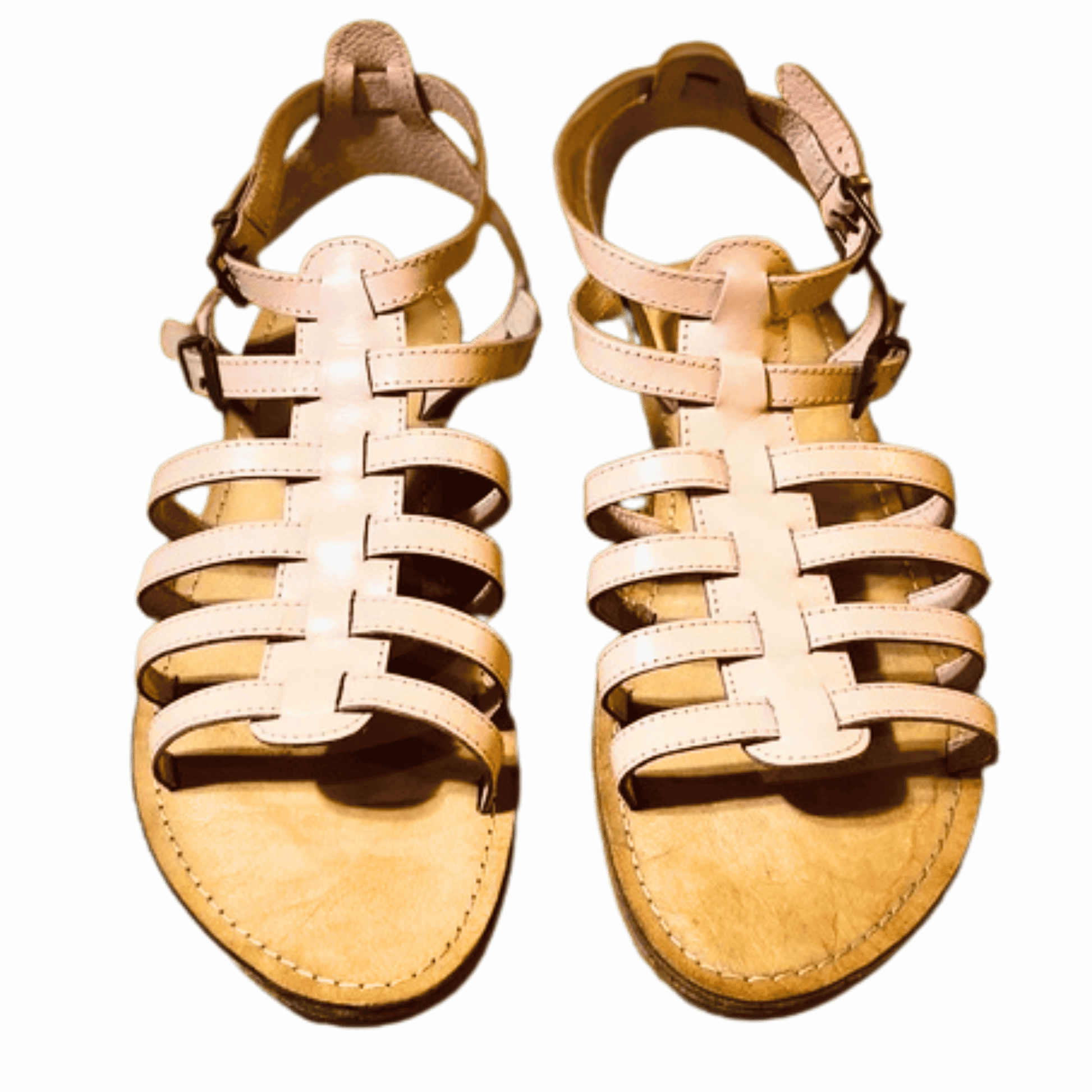 Pair of tan sandals with braided straps on a black background