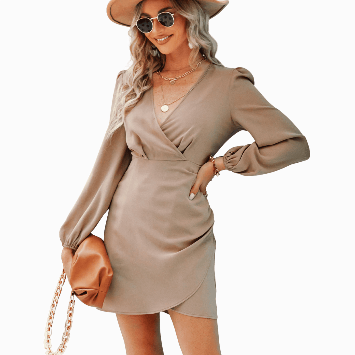 Woman wearing a beige dress with long sleeves, holding a brown handbag against a dark background